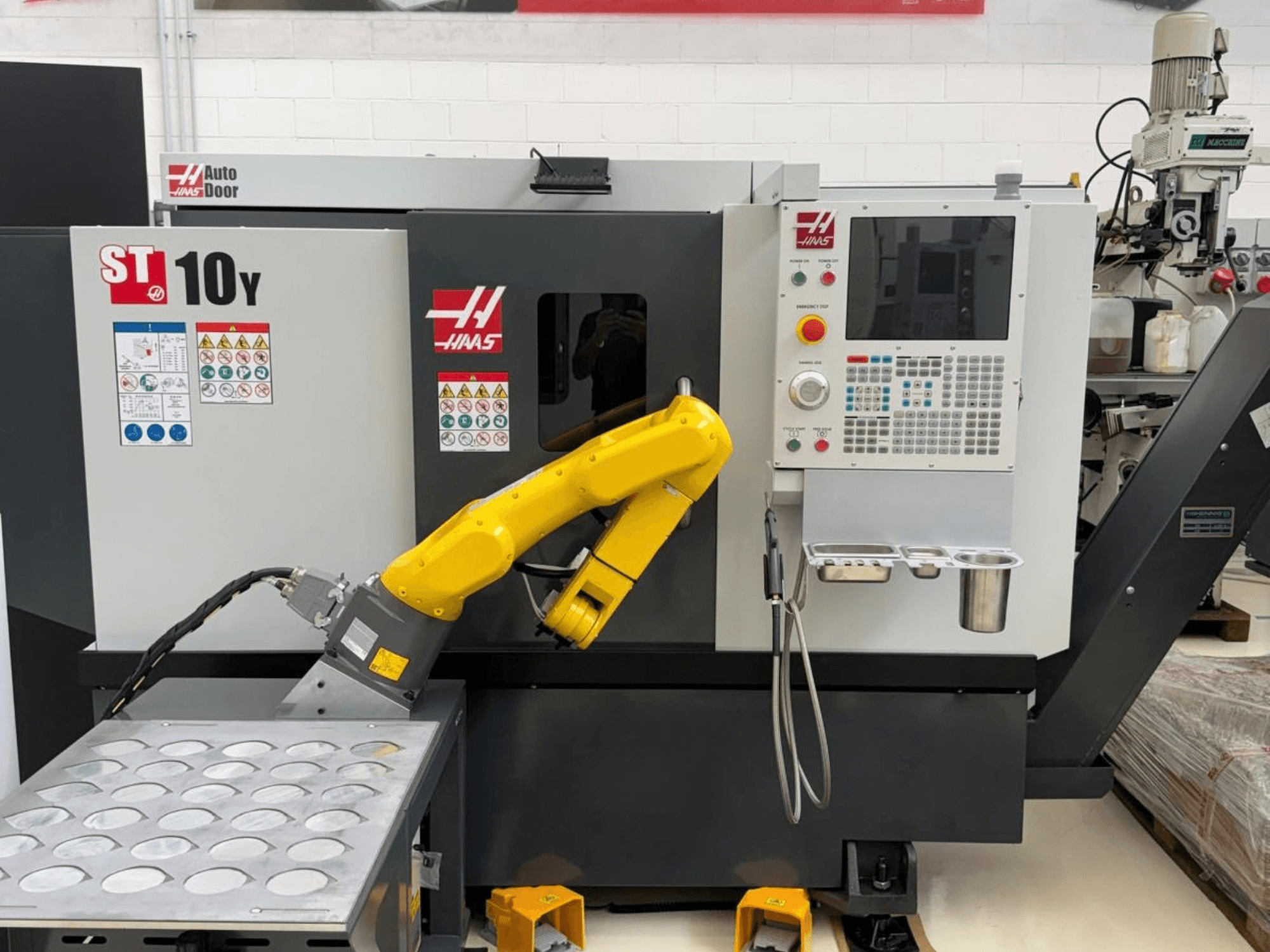 Haas ST-10Y horizontal turning machine viewed from the front, featuring a robotic arm and control panel with toolholder trays.