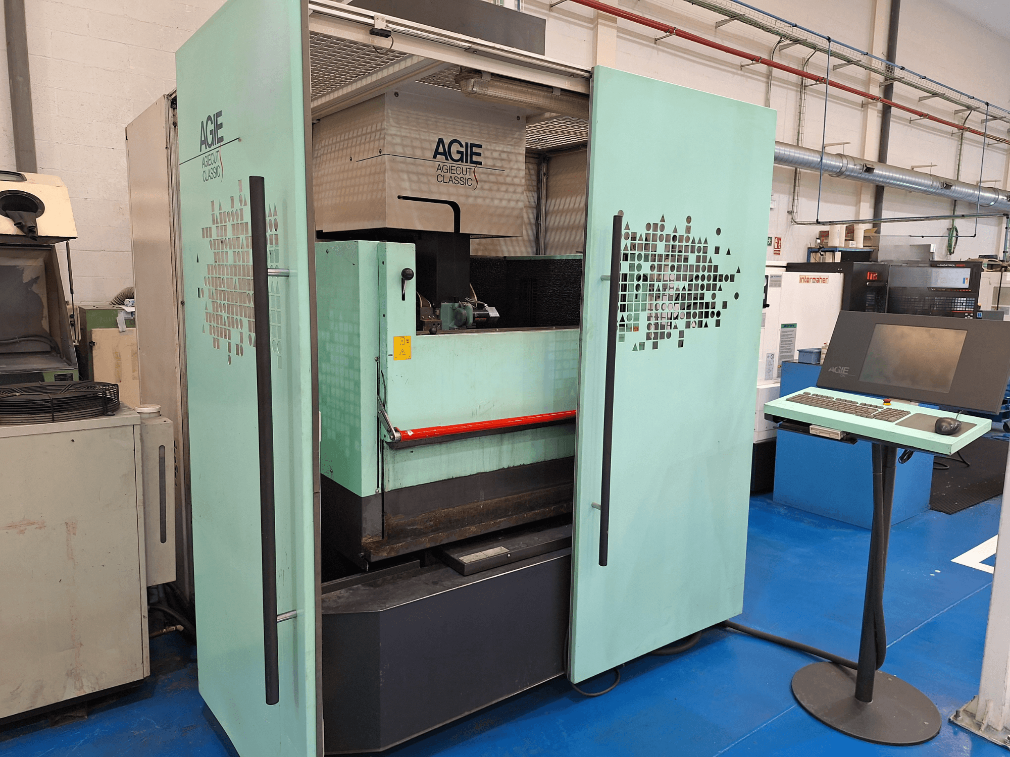 AGIE Classic 3s Wire EDM machine in front view, featuring a mint green exterior and a control panel on a stand.