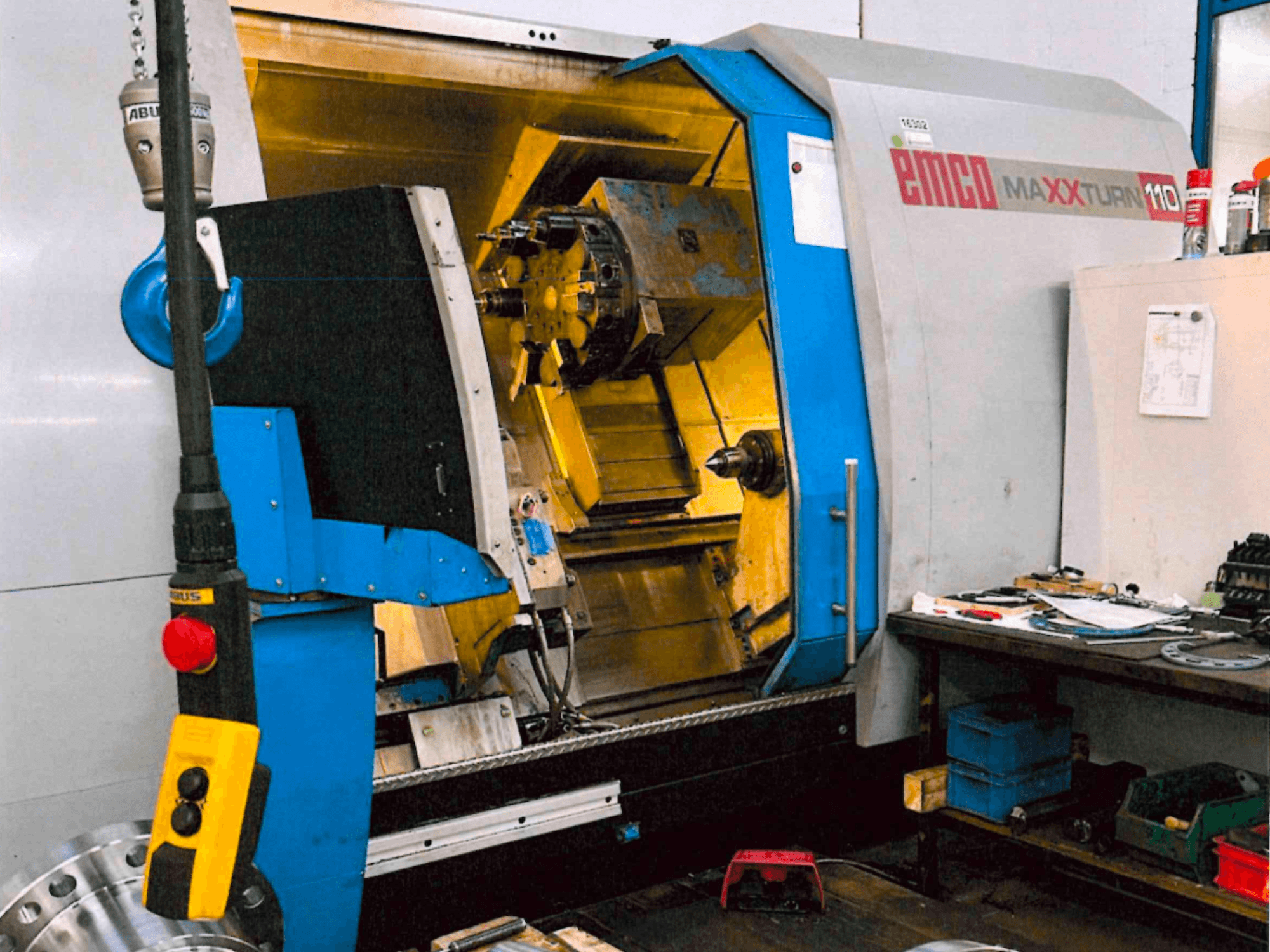 Horizontal EMCO MAXTURN 110 turning machine, front view, showing internal components and control panel, in workshop setting.