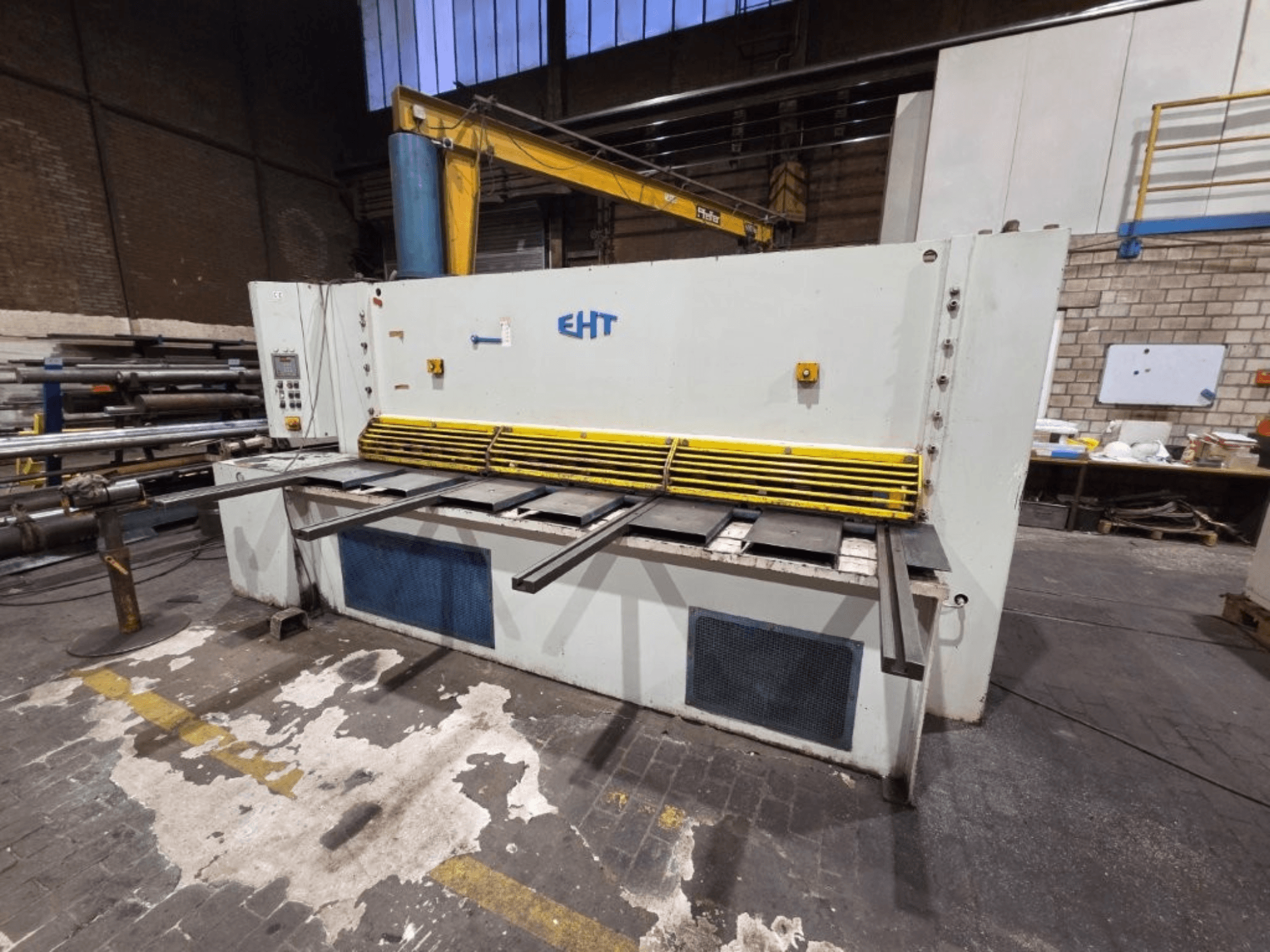 EHT hydraulic shear machine viewed from the front, featuring yellow safety guard and operational panel with controls.