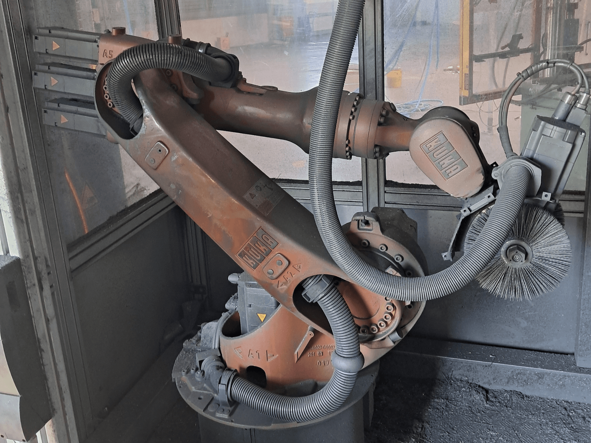 KUKA KR 16-2 robotic arm in a side view, showcasing cables, brushes, and mechanical joints, set in a work environment.