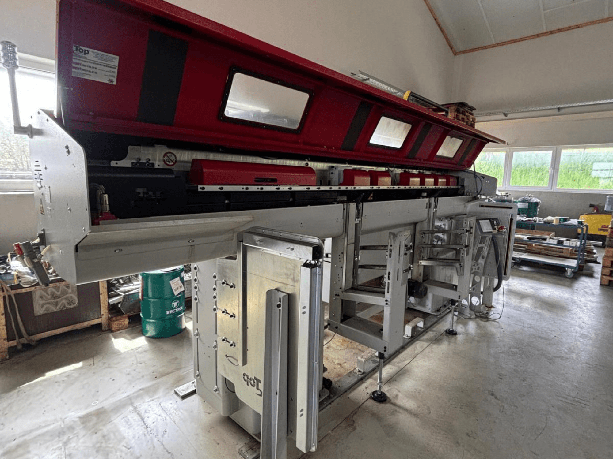 TOP Automazioni Top Loader ETL 10-75 shown from the side, featuring a red top section and complex machinery components.