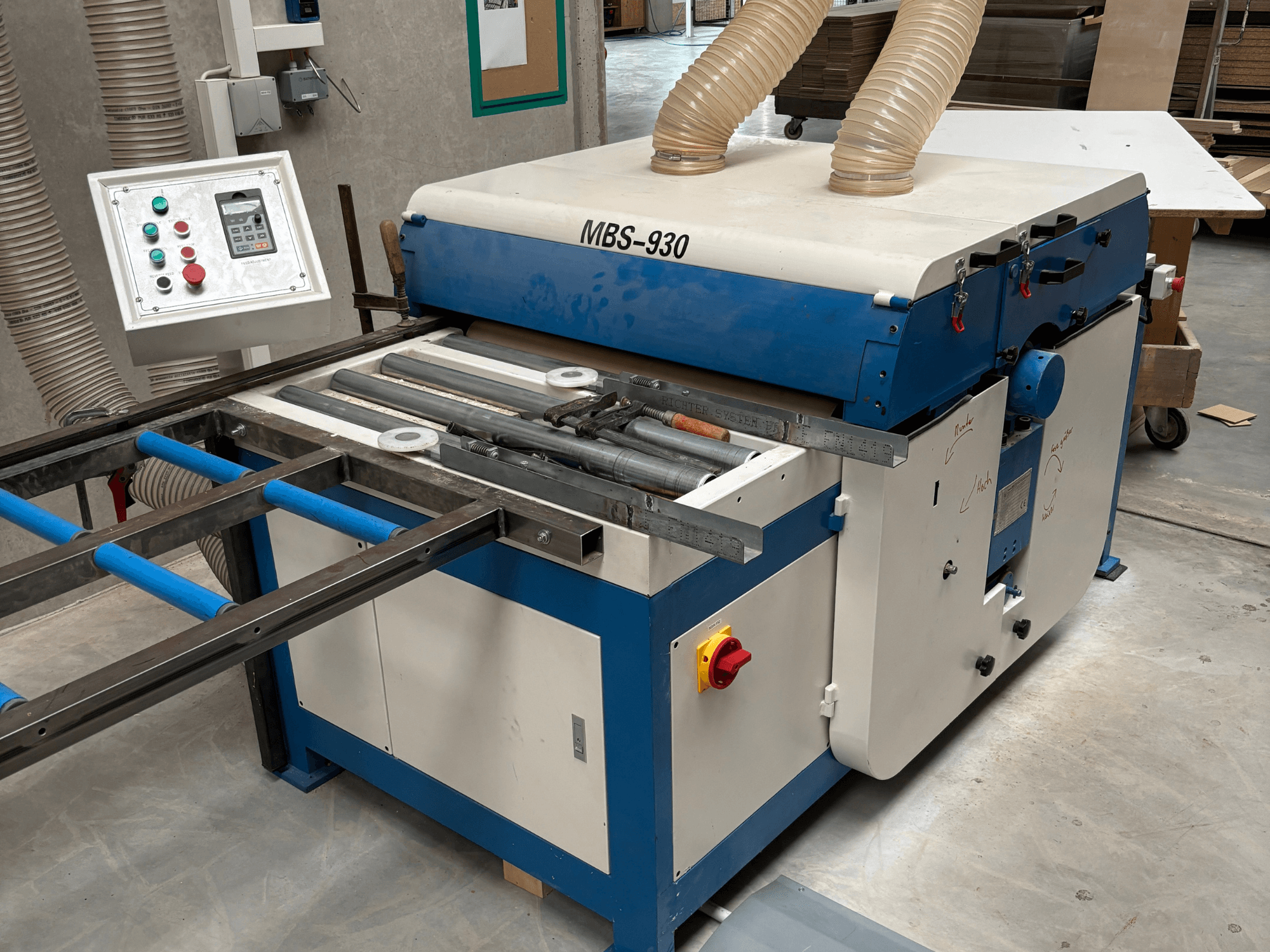 MBS-930 woodworking machine with control panel and rollers, viewed from the side, featuring dust extraction hoses.