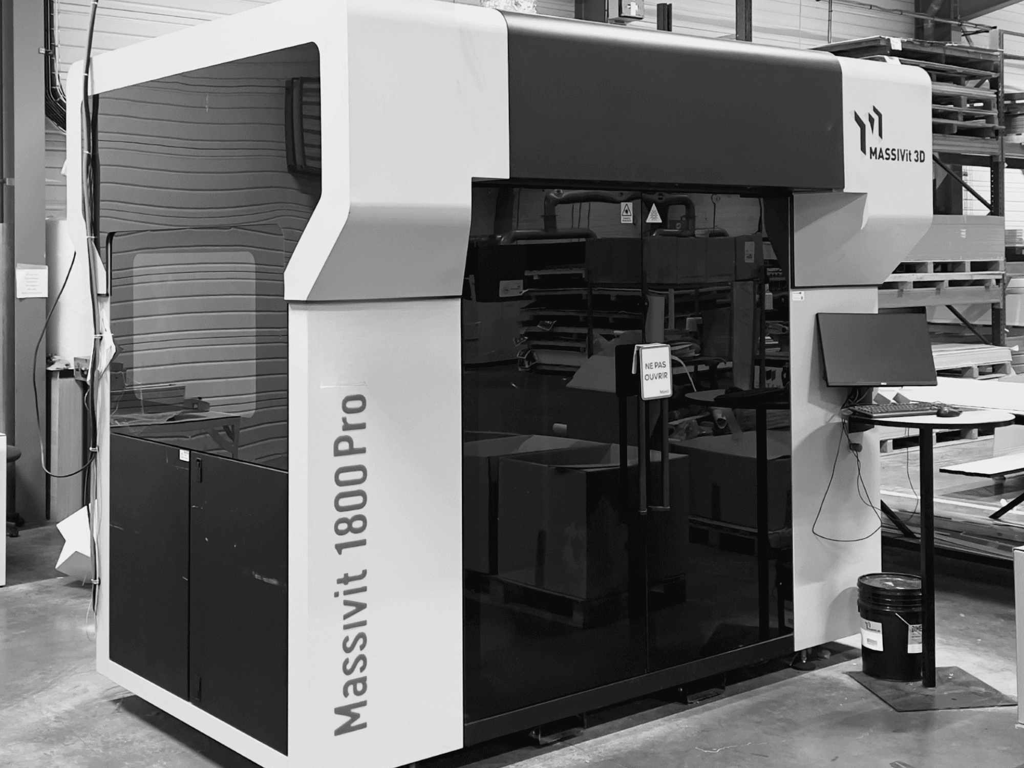Plastic 3D printer MASSIVIT 1800 PRO in a workshop, front view, with a computer workstation and control panel visible.