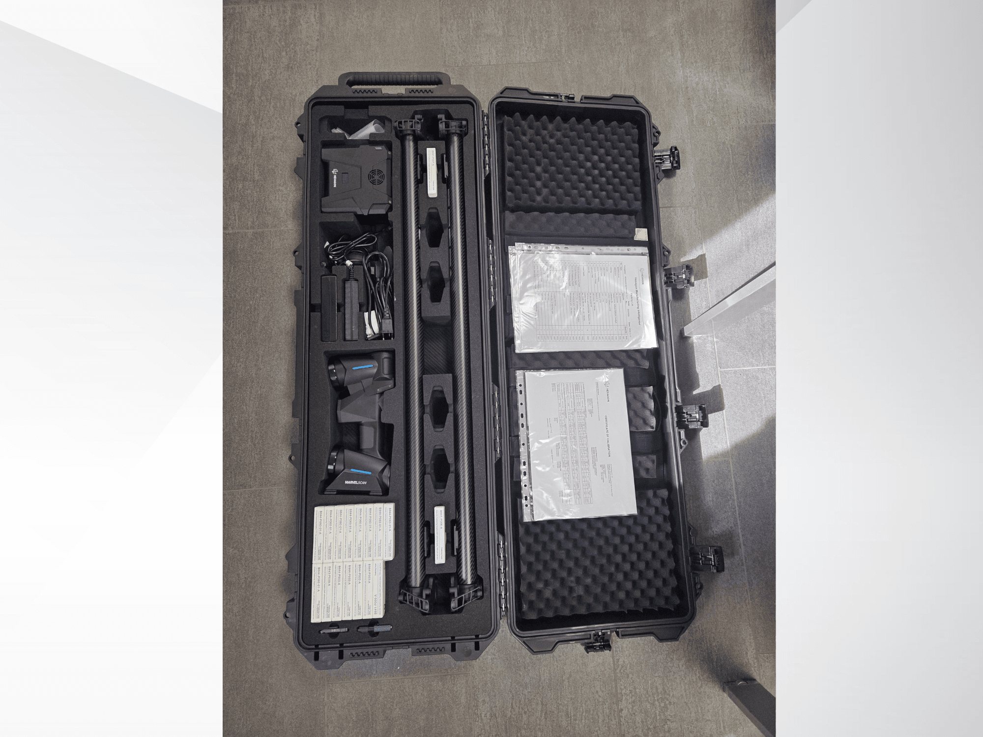 Hexagon MARVEL CMM equipment in a black case, featuring multiple sensors, cables, and documentation, top-down view.