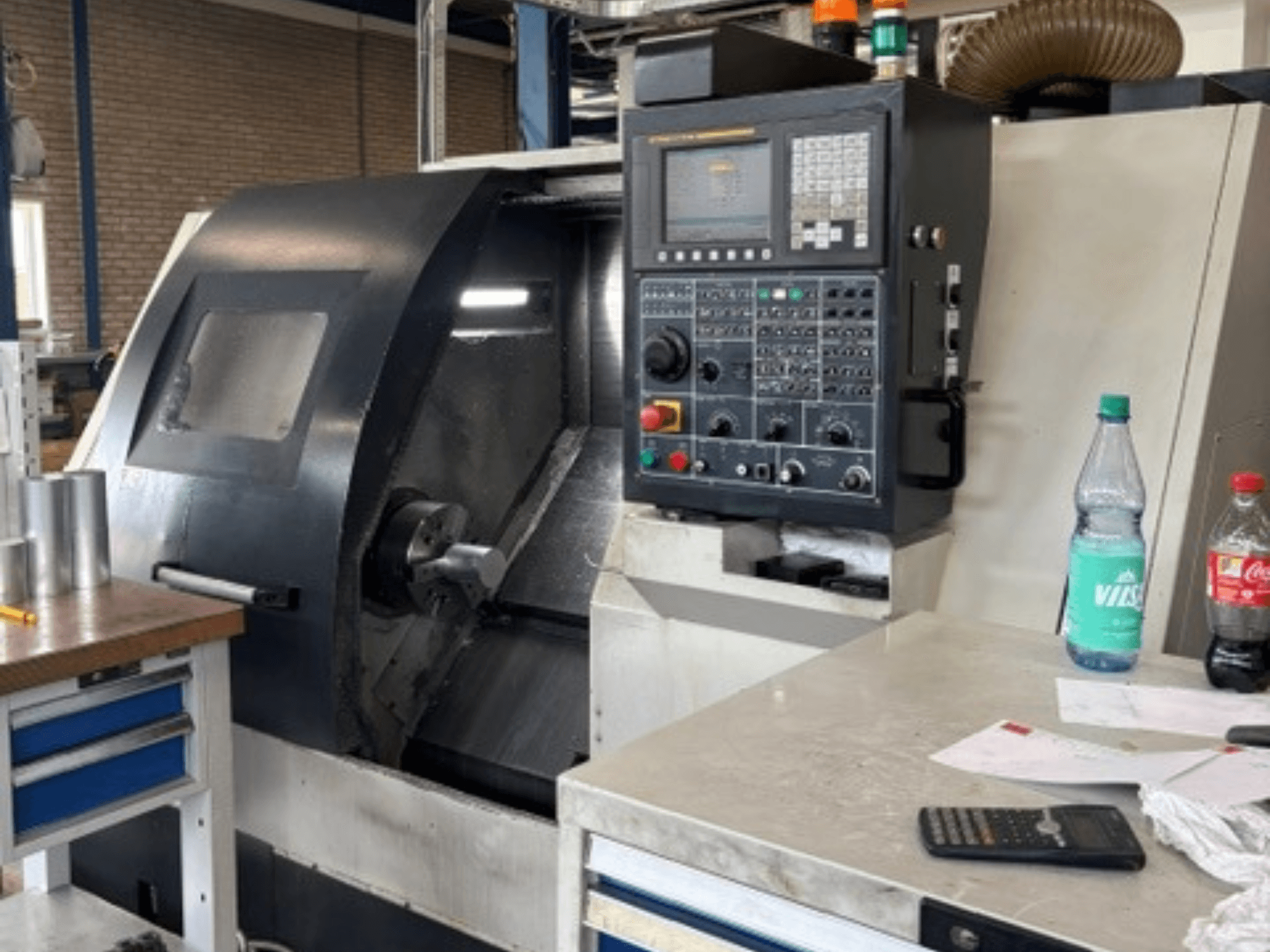 Leadwell T-7 horizontal turning machine, front view, with control panel, workpiece on tool rest, and workspace details visible.