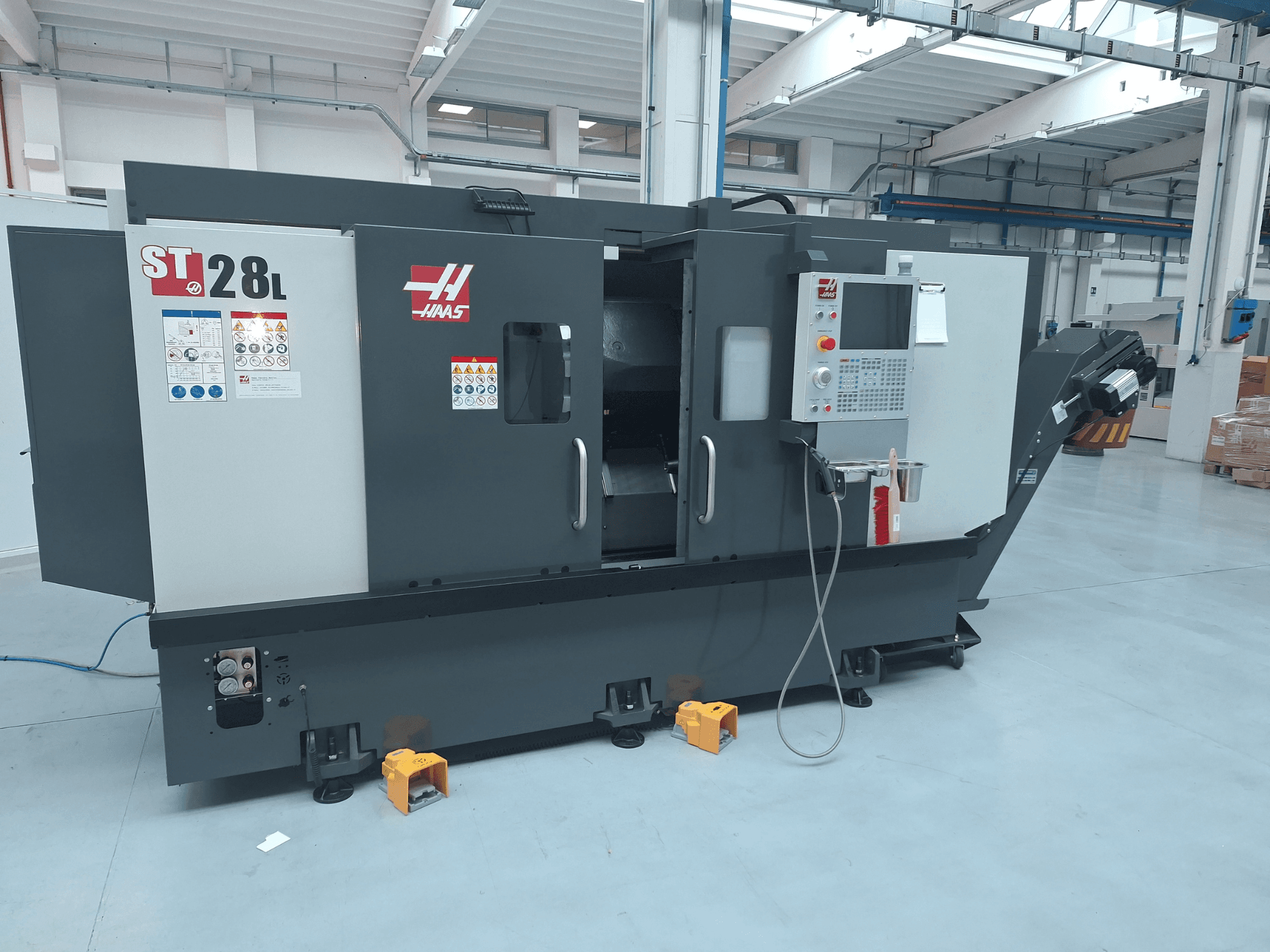 Haas ST-28L horizontal turning machine side view, featuring control panel, operational buttons, and safety labels.
