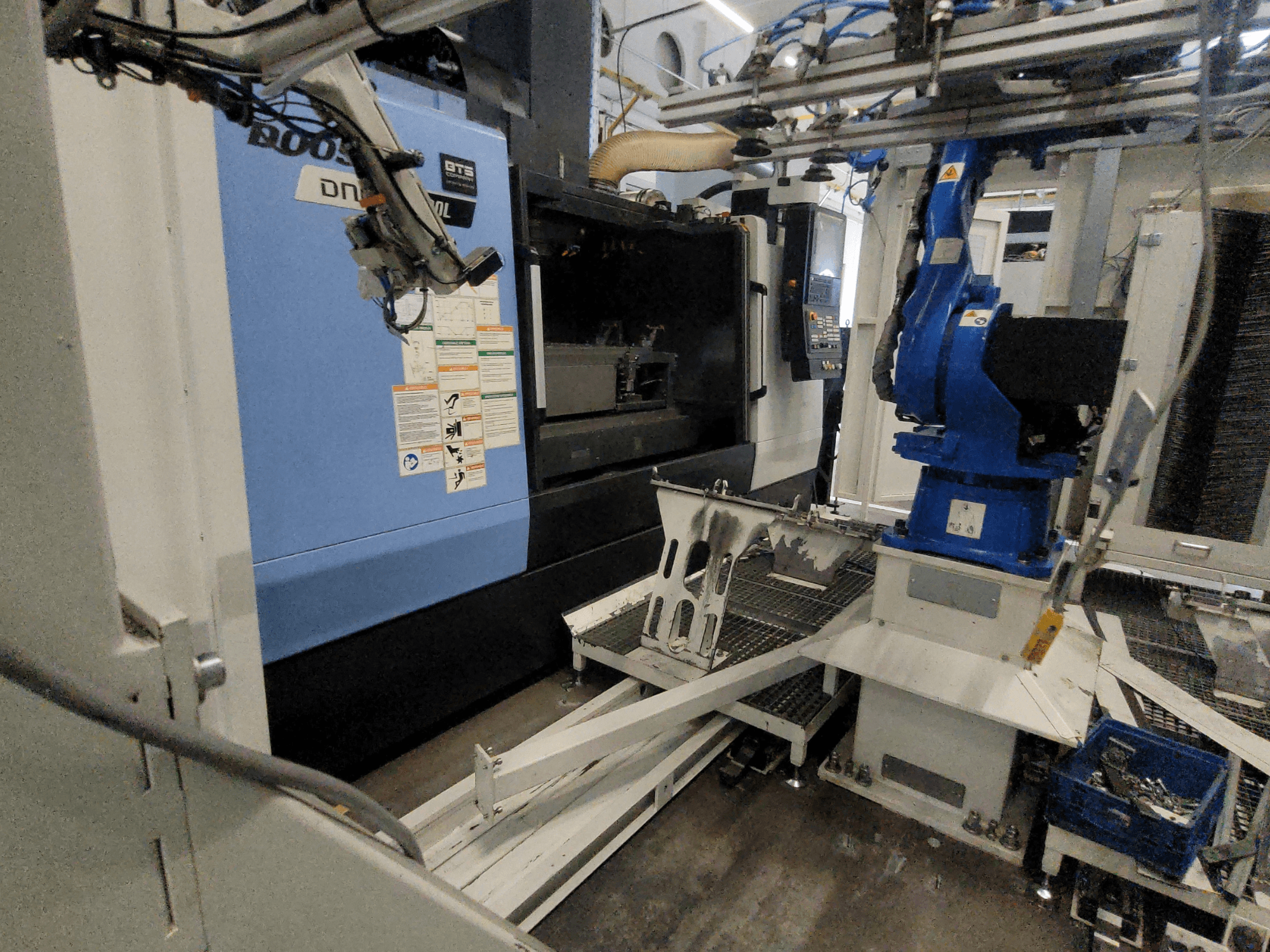 DOOSAN DNM 6700L Vertical Machining Centre side view, with robotic arm and control panel visible, showcasing machinery setup.