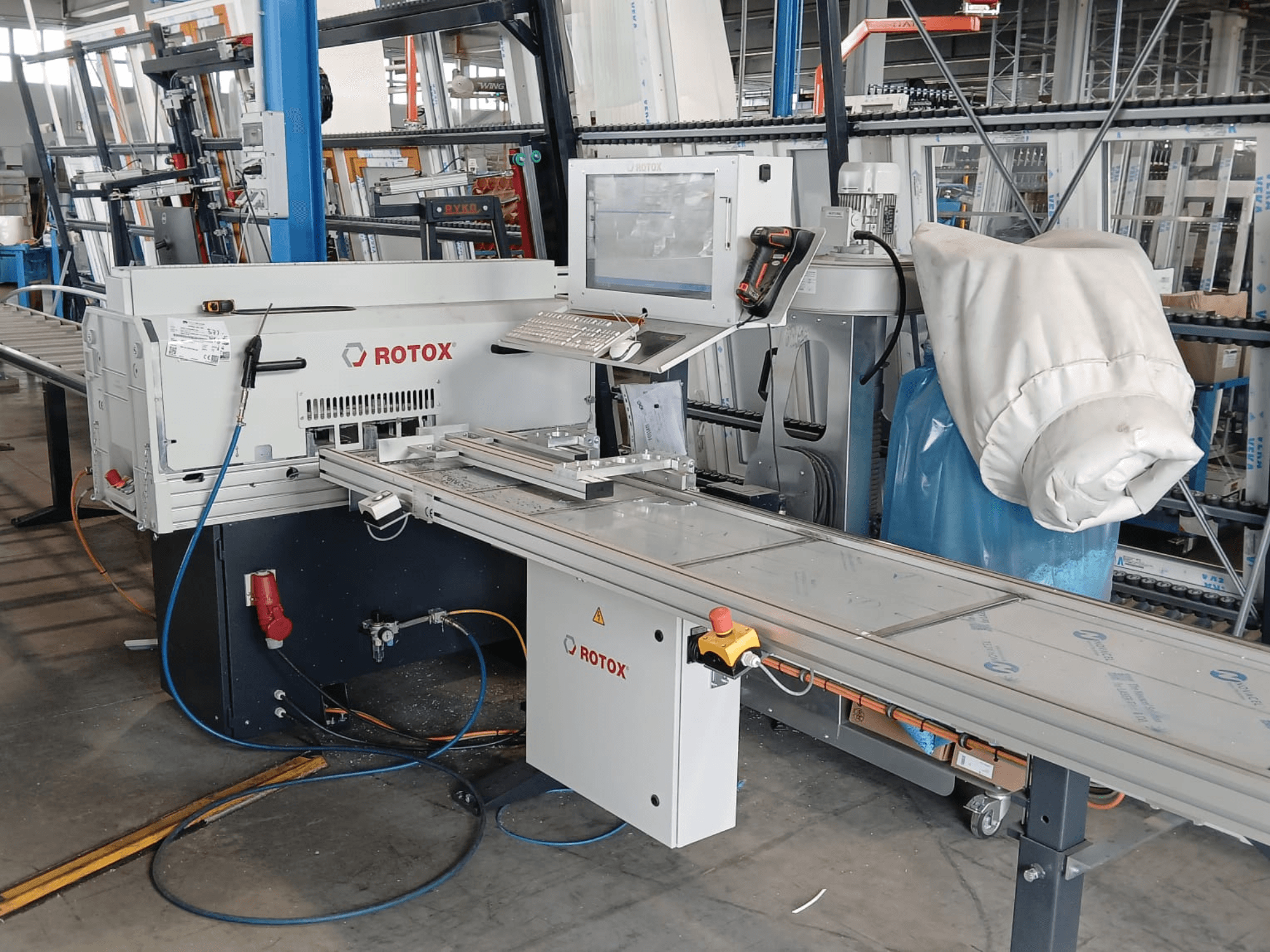 Front view of a Rotox GLA401 plastic processing machine with control panel, conveyor, and visible hoses in an industrial setting.