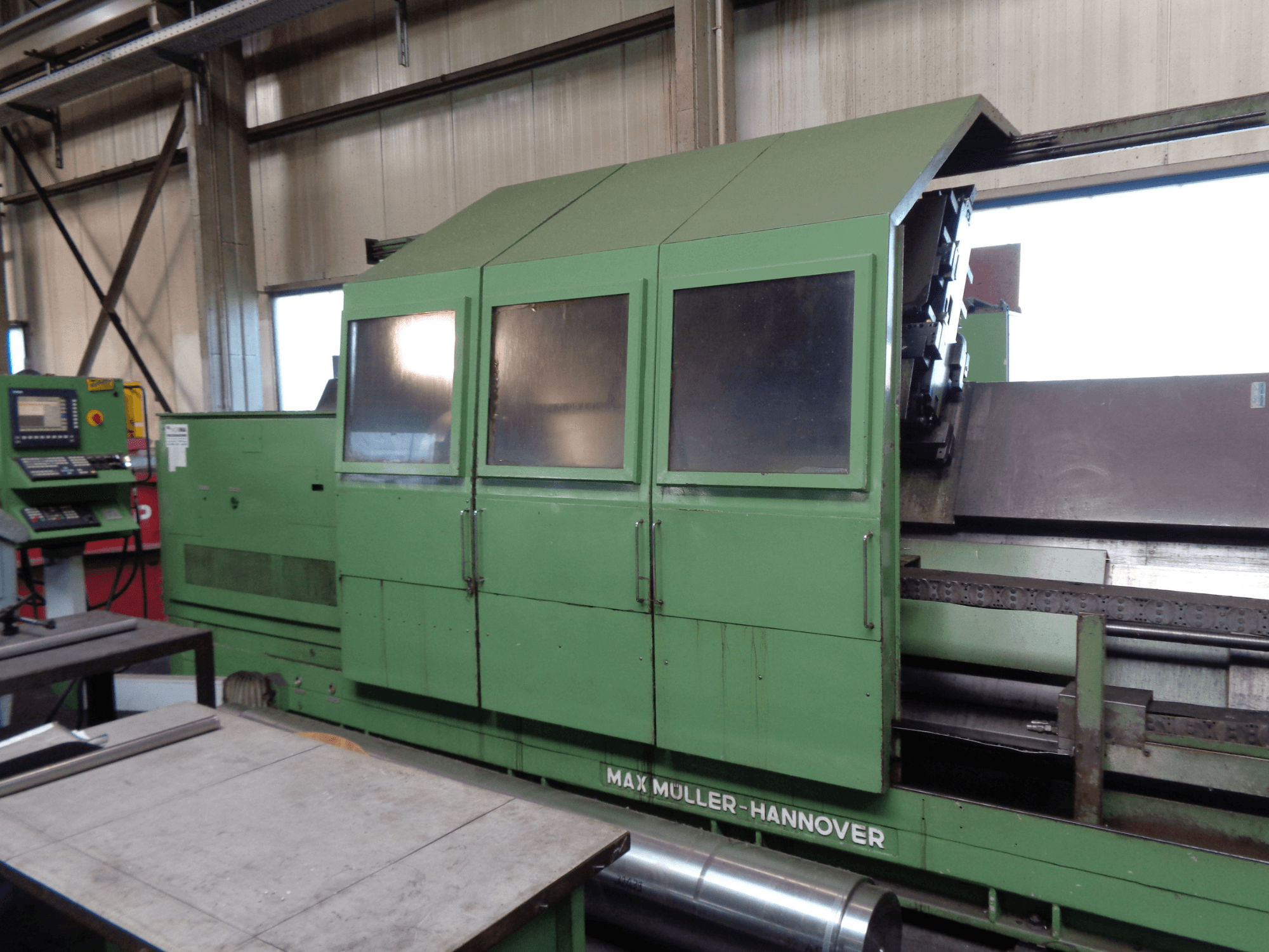 MAX MULLER 3000 Turn-Mill Centre in green, side view with control panel. Large machining area and windowed enclosure visible.