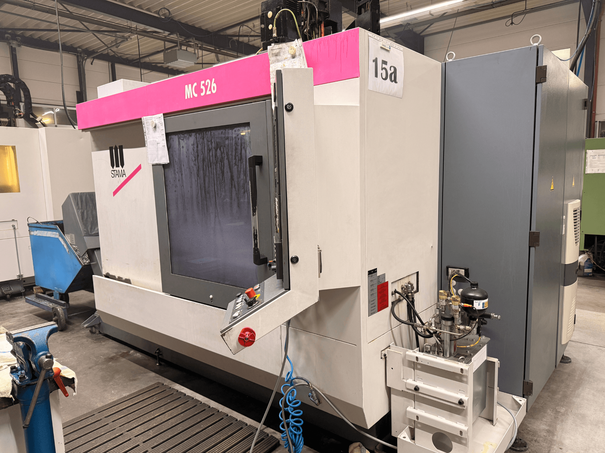 Stama MC 526 machining center in a workshop, front view, featuring control panel and adjacent grey electrical box.
