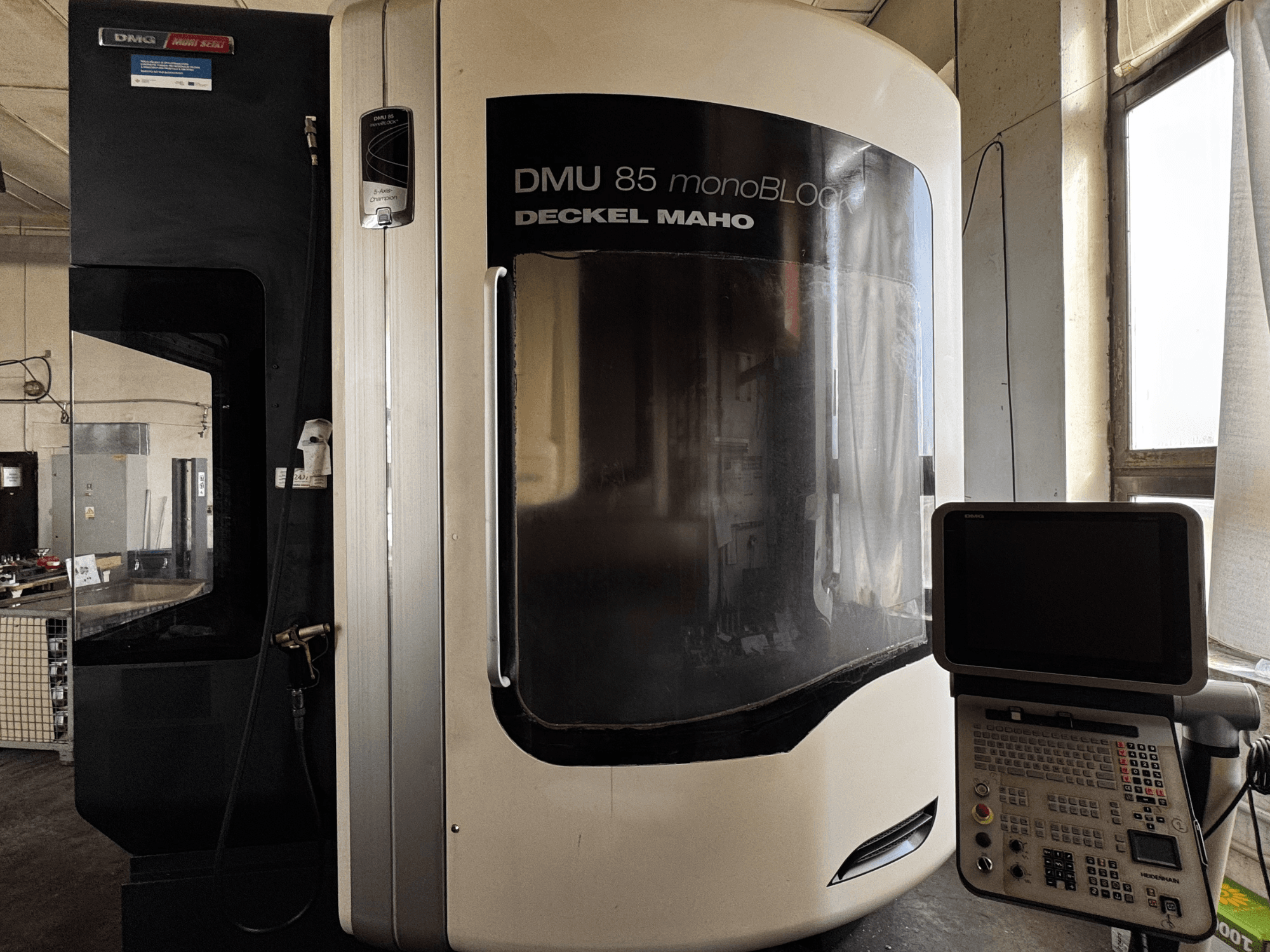 DMG MORI DMU 85 monoBLOCK vertical machining center, front view with control panel and large viewing window.