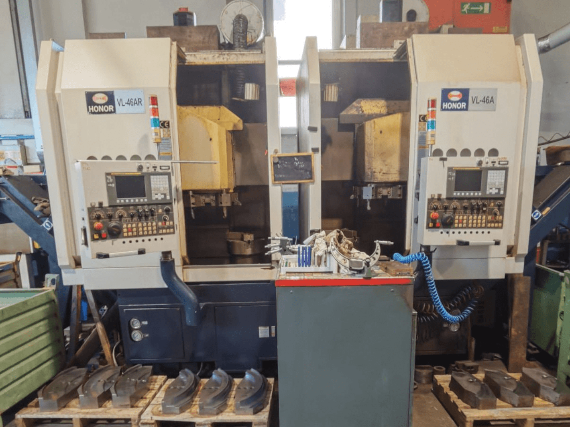 Front view of HONOR SEIKI VL 46A Vertical Turning Machine, displaying control panel and surrounding parts on wooden pallets.