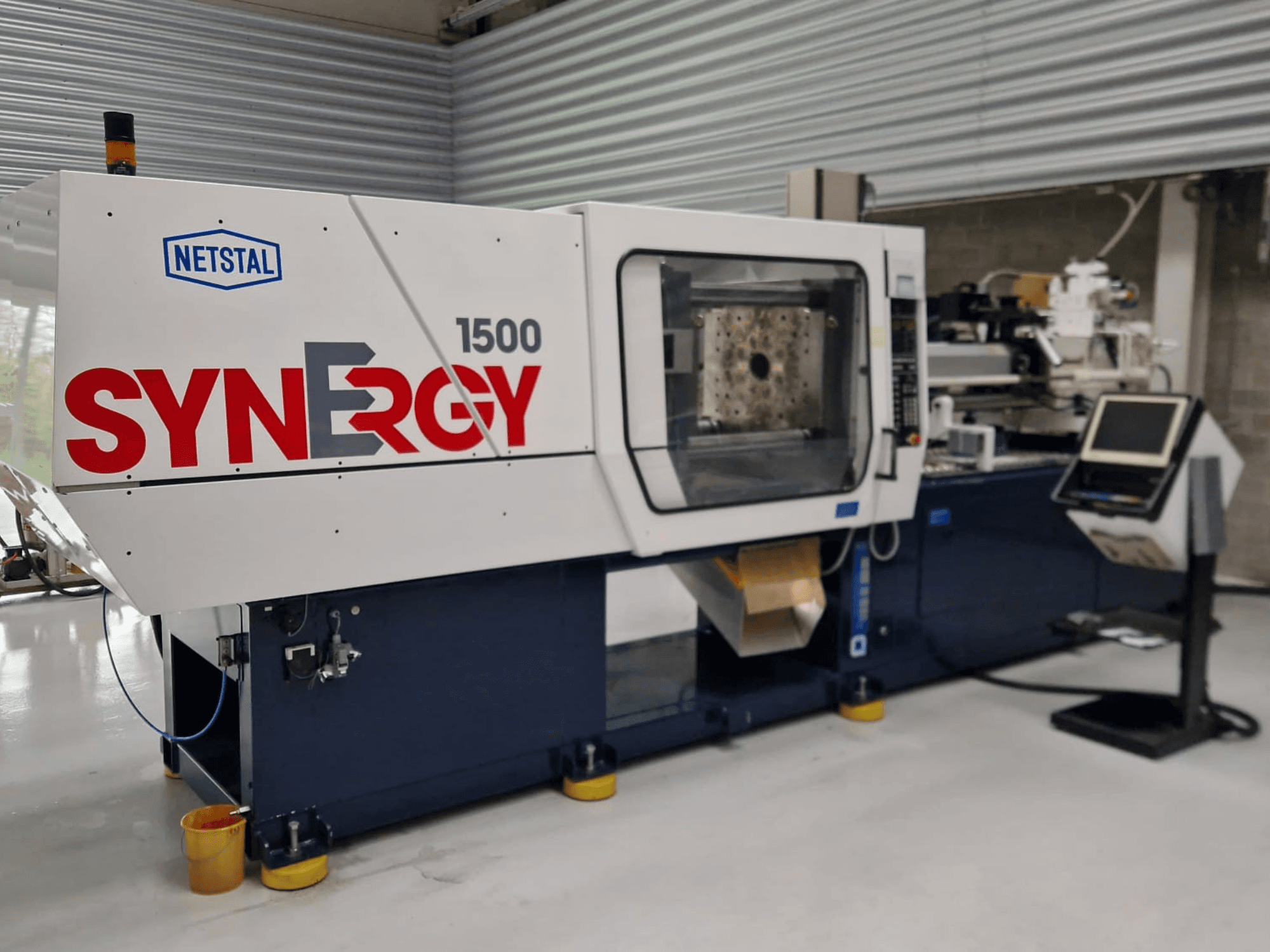 Netstal Synergy 1500-460 hydraulic injection moulding machine, front view, showcasing control panel and open injection area.