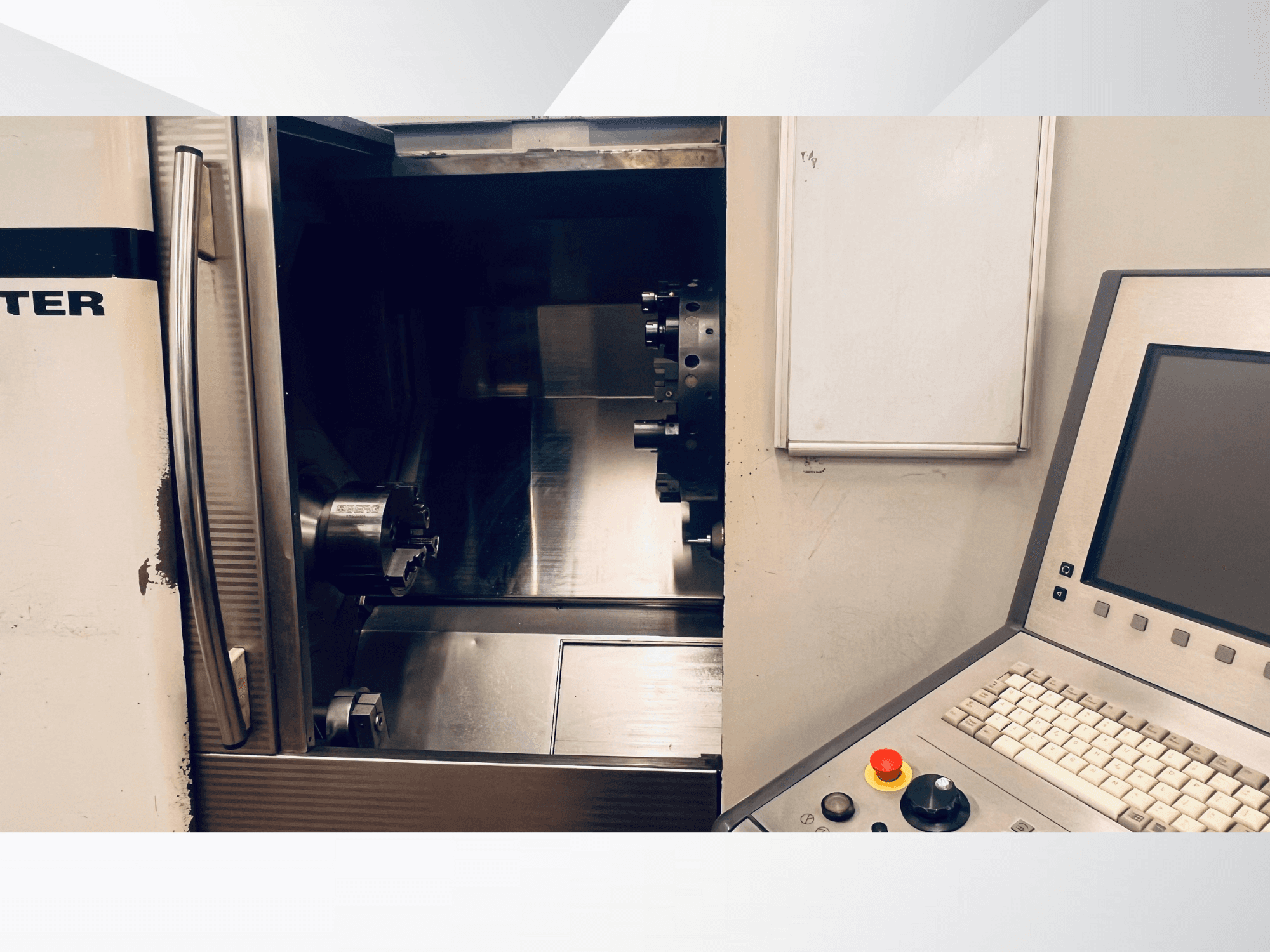 CNC machine front view showing the open chamber and control panel with a keyboard and emergency stop button.