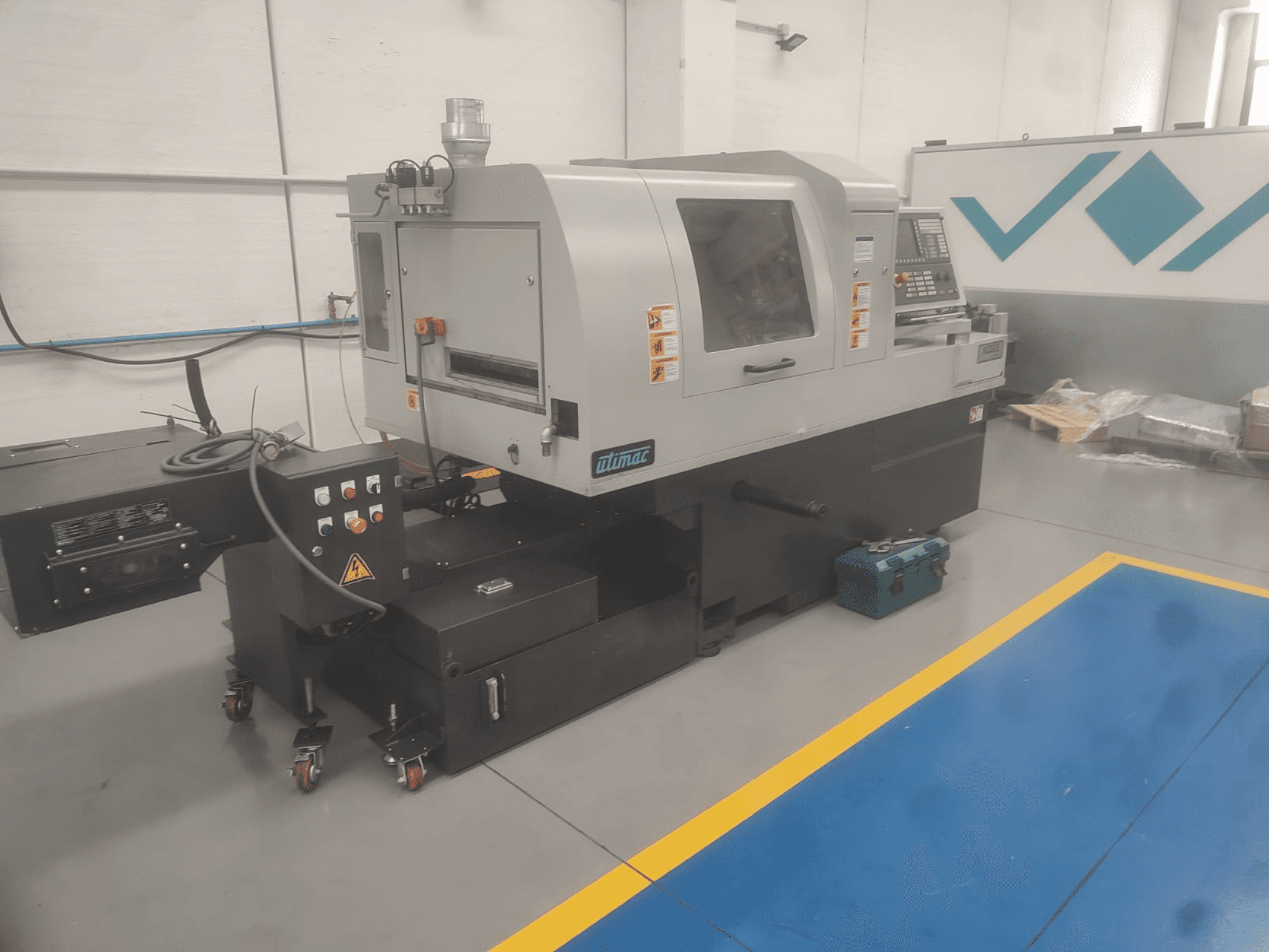 UTIMAC ISOLA XD 38 II Swiss type turning machine, front view, featuring control panel and wheeled base for mobility.