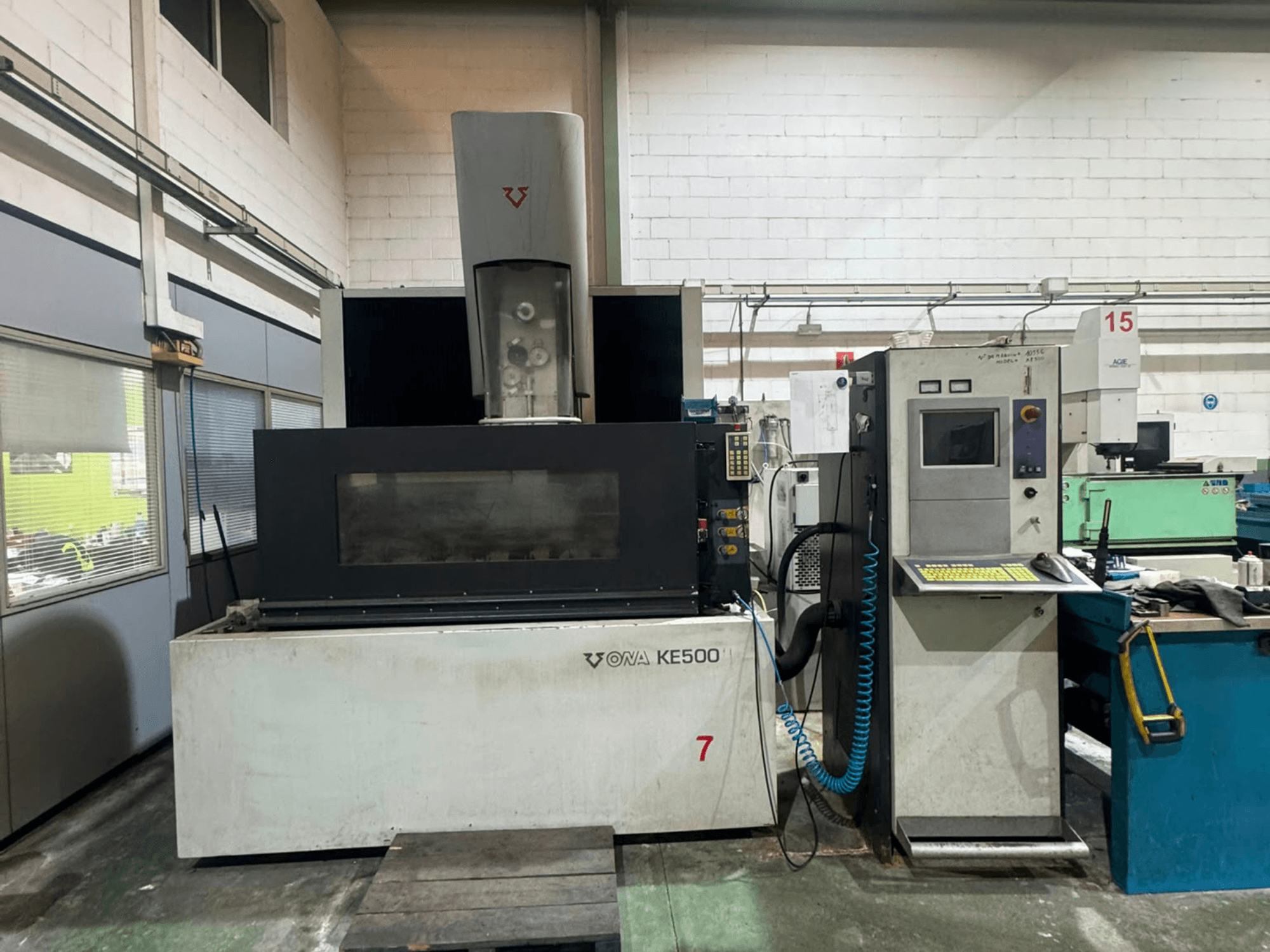 ONA KE500 Wire EDM machine in front view, featuring a control panel, cutting area, and central coolant spindle.