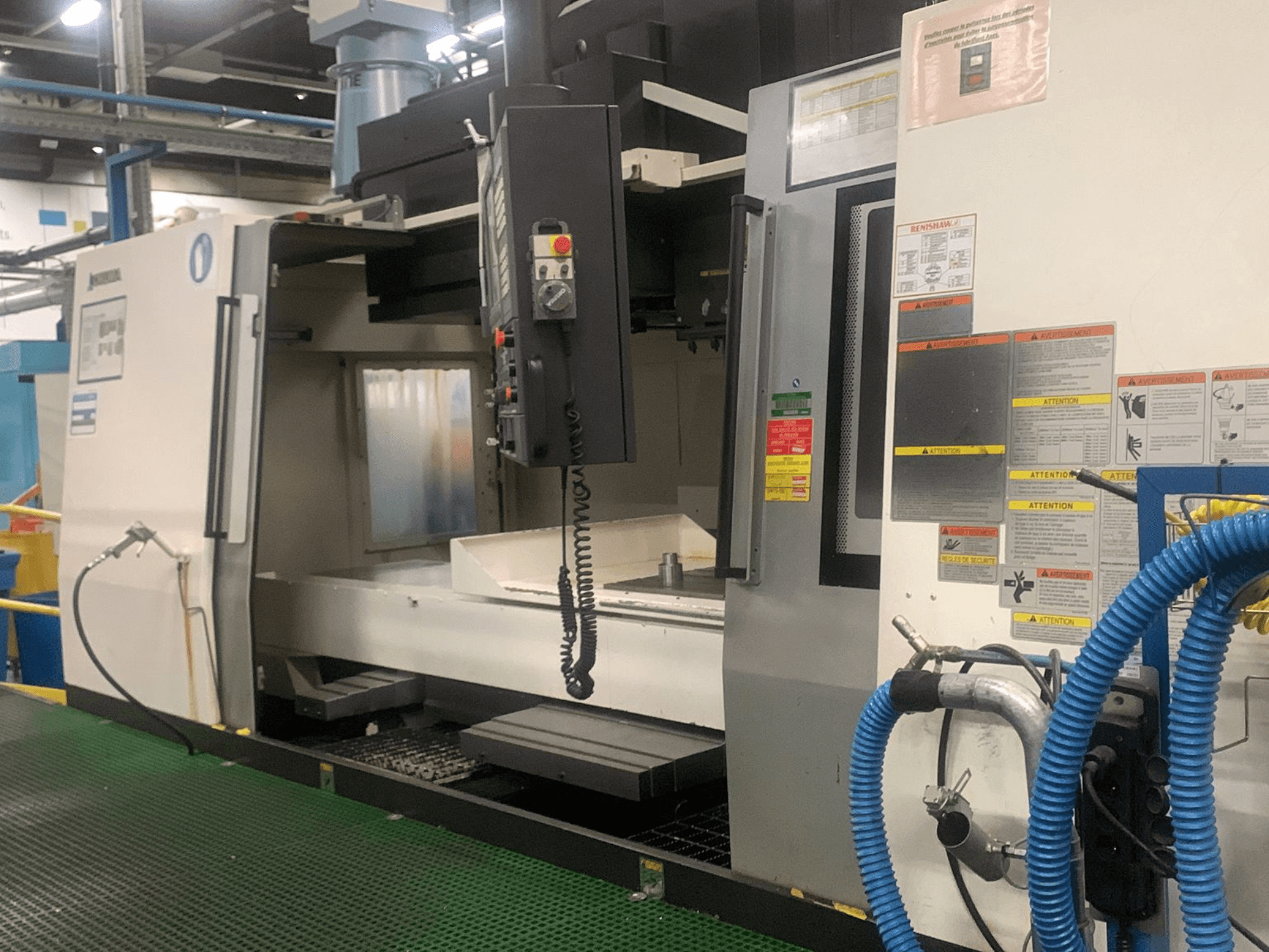 Okuma Millac 852 VII vertical machining center, front view, showing control panel, spindle area, and safety labels.