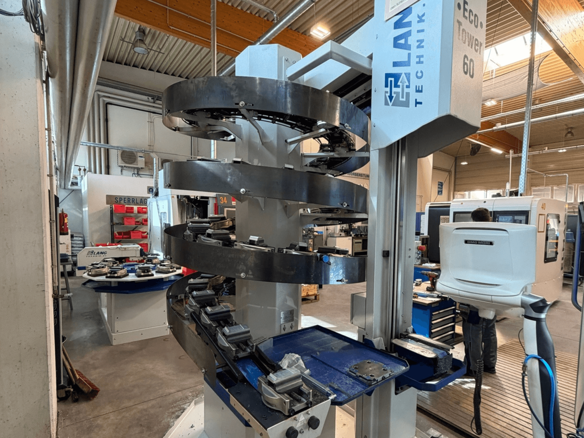 LANG Eco-Tower 60 workpiece handling system in a manufacturing setting, showcasing spiral conveyors and assembly stations.