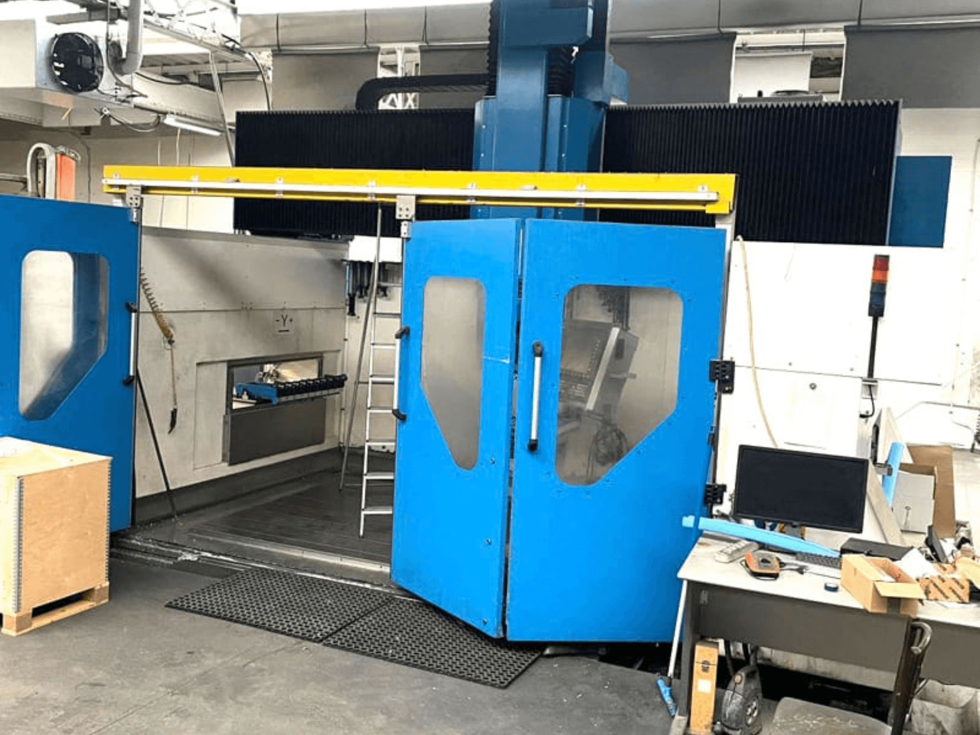 Front view of TECHMILL LABOR SHAPE 3220 vertical machining center with blue doors open, revealing the work area inside.