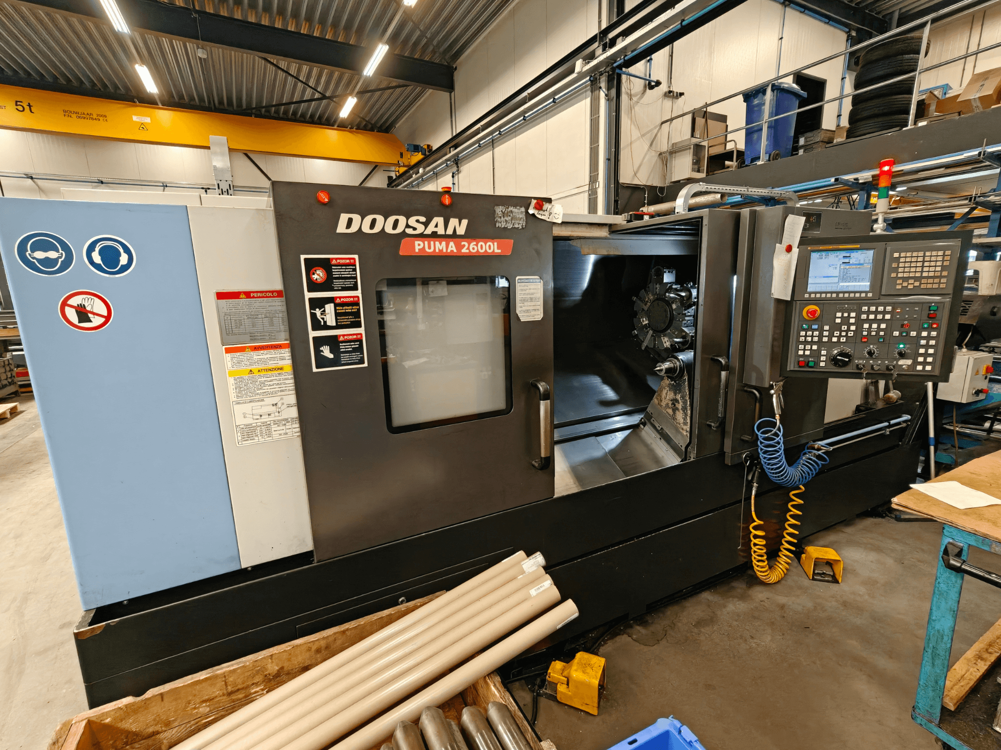 DOOSAN Puma 2600L horizontal turning machine in a workshop, side view showing control panel and spindle area.