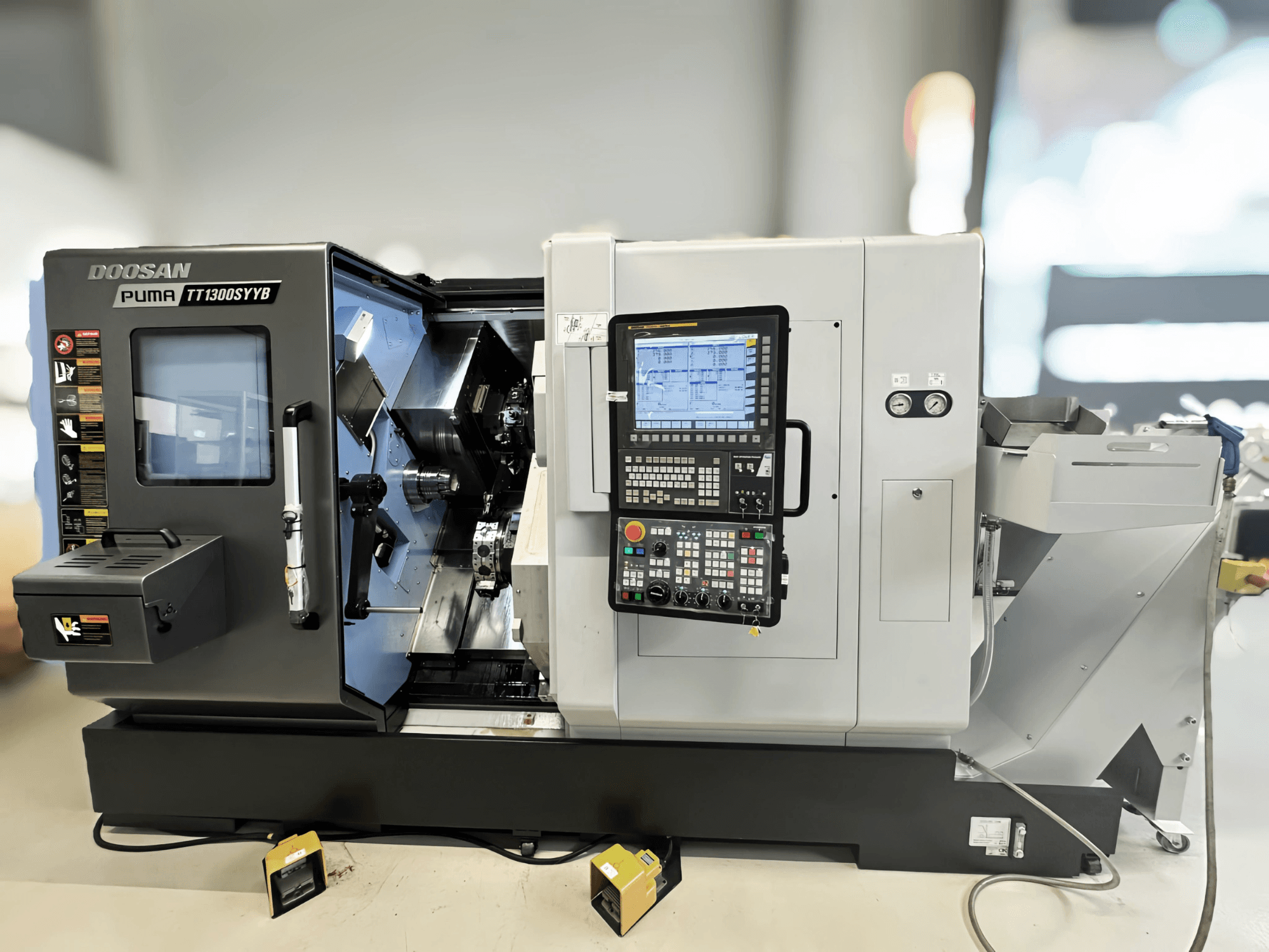 Doosan Puma TT1300SYYB turn-mill centre in side view, showcasing control panel and machine interior with tools visible.