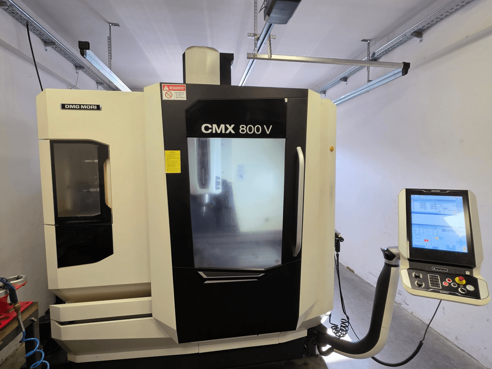 DMG MORI CMX 800V vertical machining center, front view, featuring a touchscreen control panel and clear safety signage.