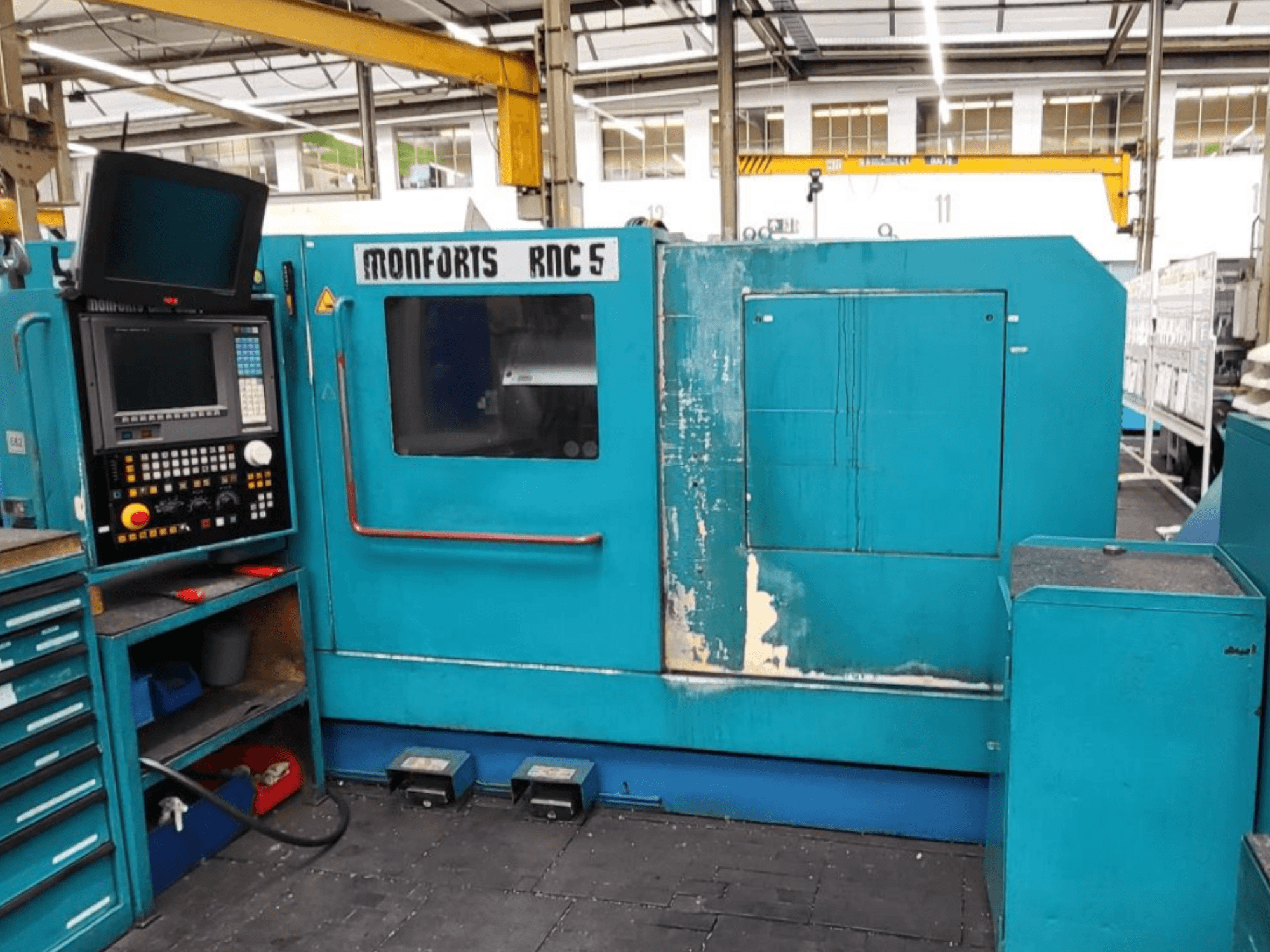 Front view of Monforts RNC 5 horizontal turning machine with control panel, blue exterior, and visible wear marks.