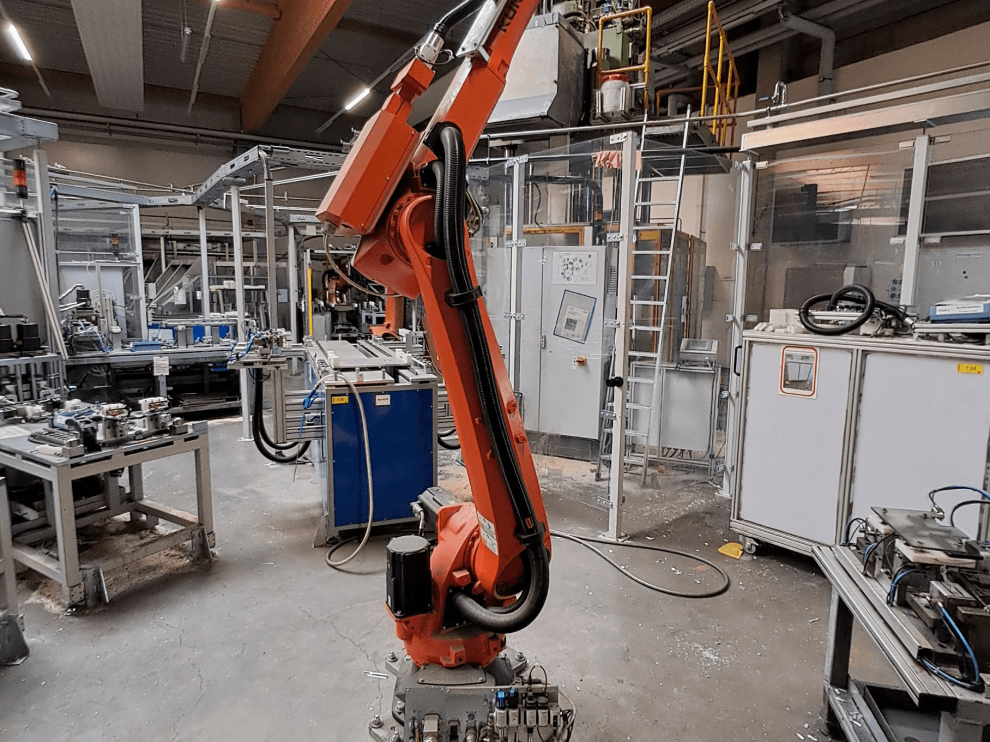 KUKA KR 26 R3100/SEL robot arm in an industrial setting, shown from a side view with operational equipment in the background.