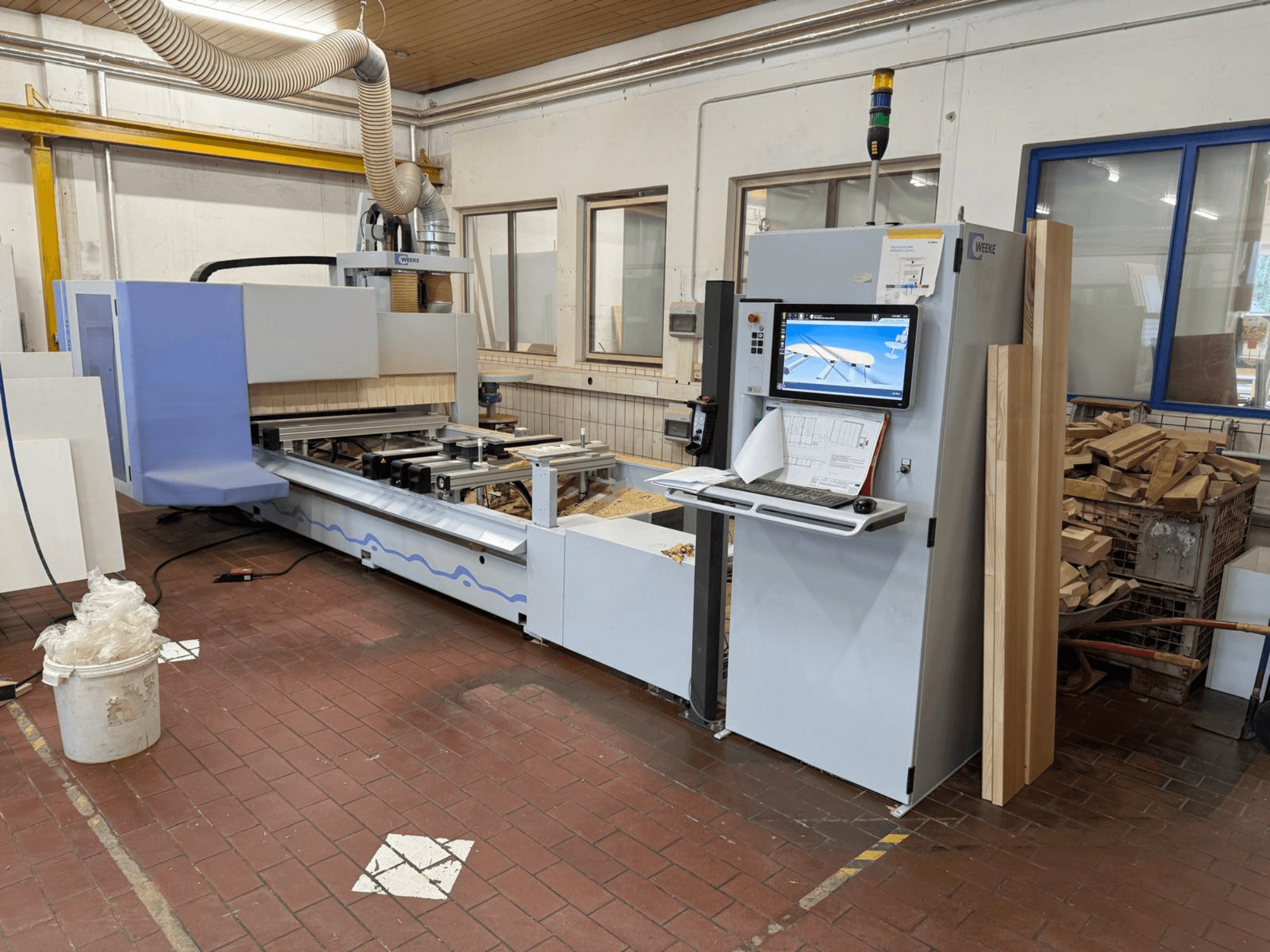 Weeke PROFI BMG211/32/12/K CNC wood machining center, front view, features control panel and wood pieces, with dust extraction system.