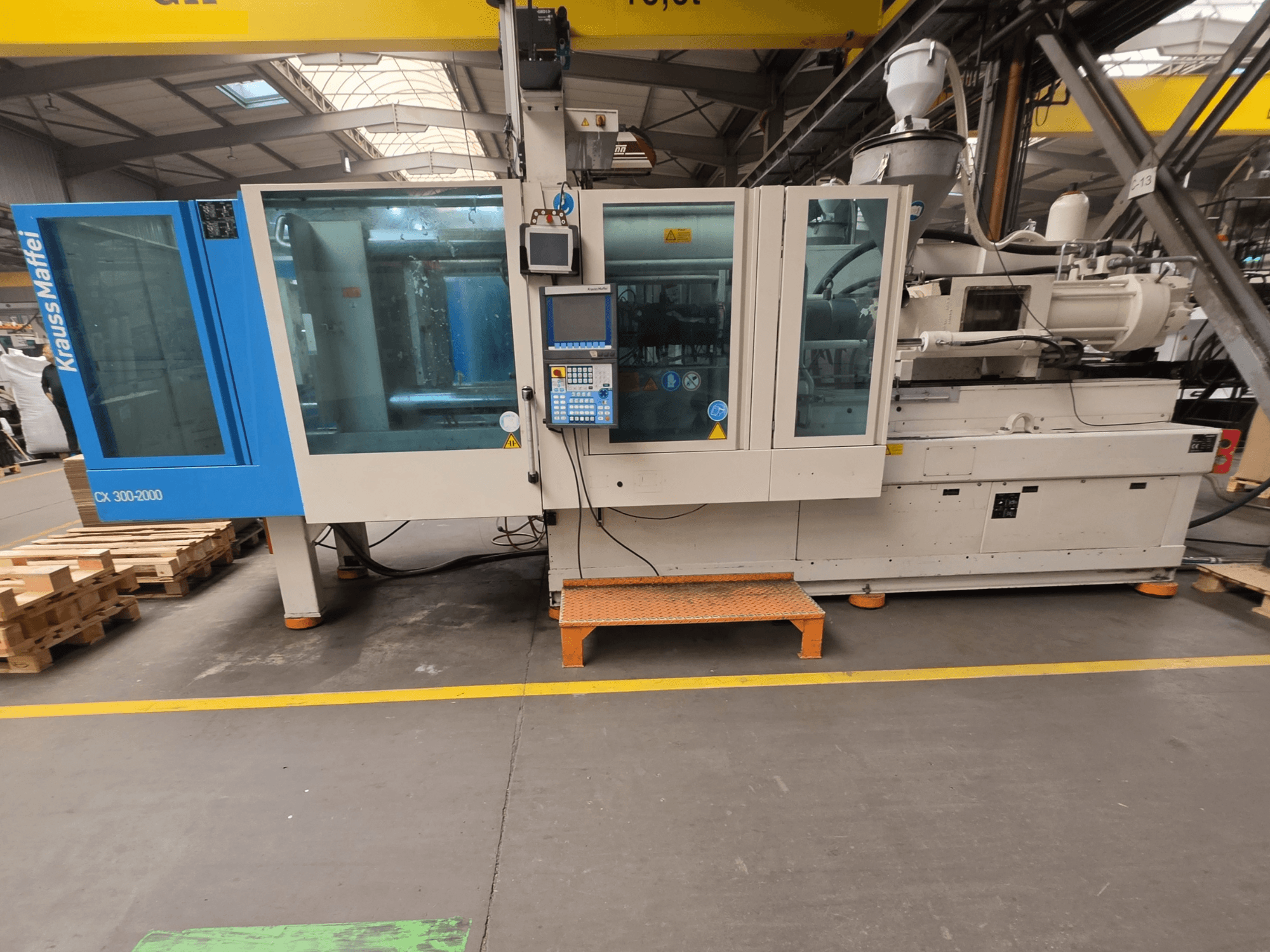 Krauss Maffei 300-2000 CX hydraulic injection moulding machine, side view showing control panel and large windows.