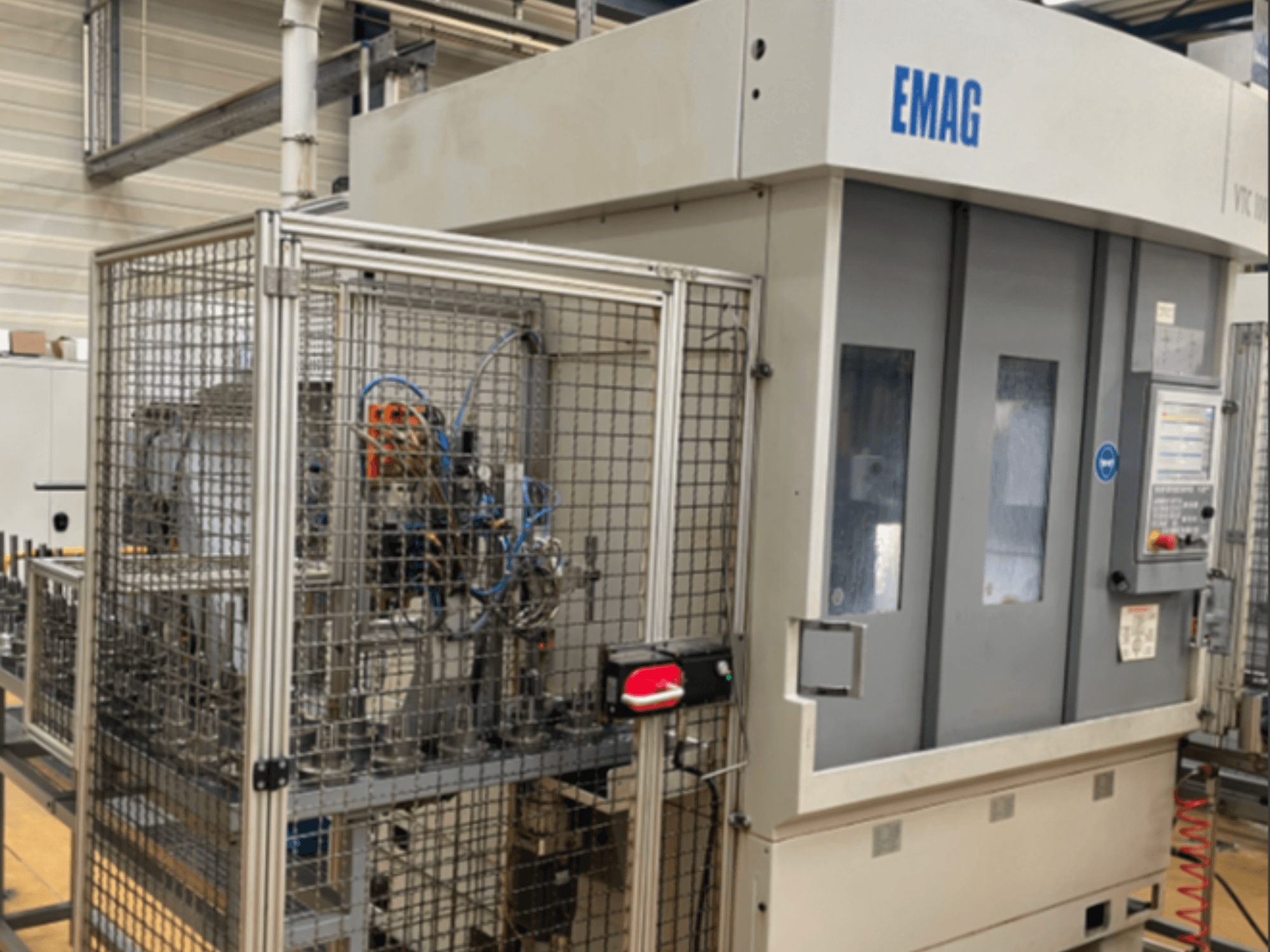 EMAG VTC 100 vertical turning machine in side view, showcasing the control panel and safety fencing details.