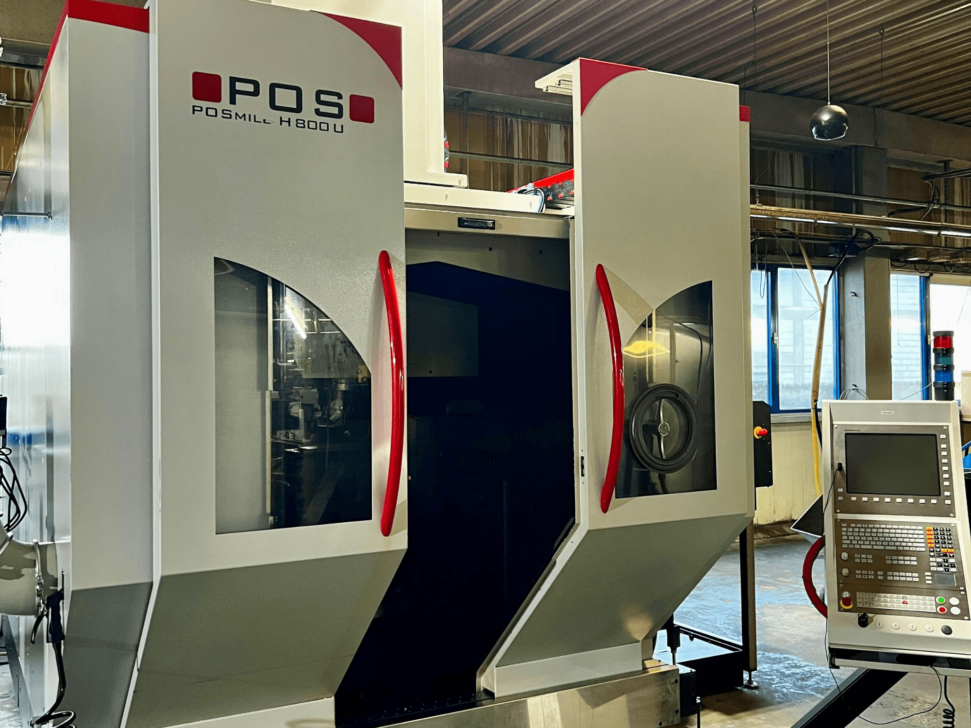 POSmill H800U Universal Machining Centre viewed from the front with control panel and open doors showcasing interior components.