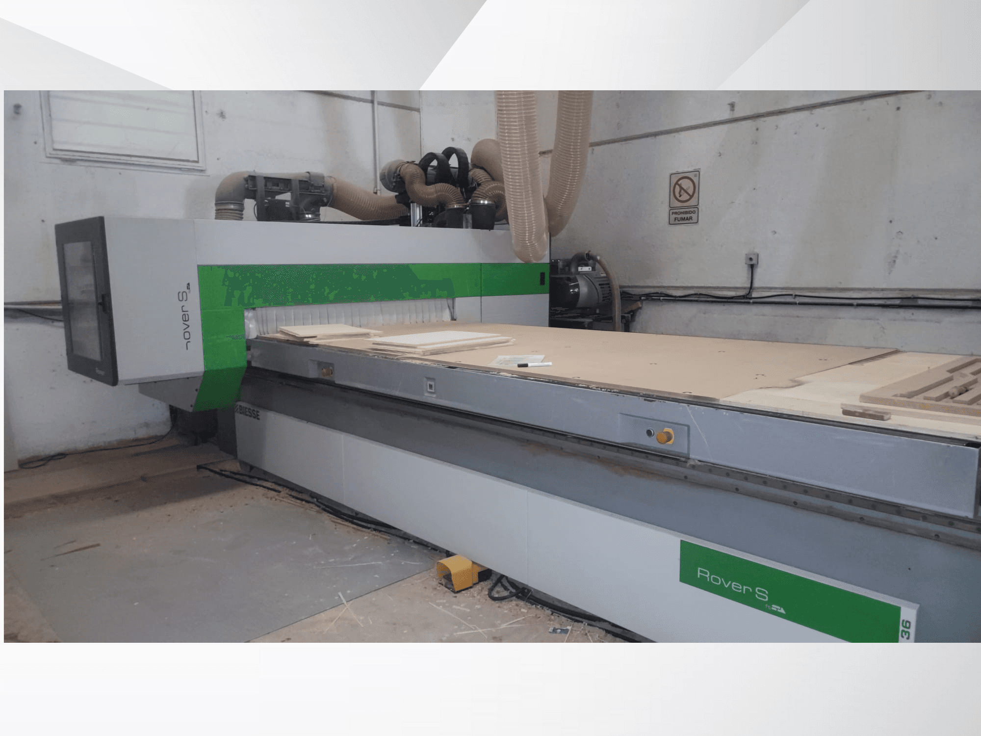 Front view of Biesse Rover S CNC machine, featuring a large work surface with wooden panels and dust extraction hoses.