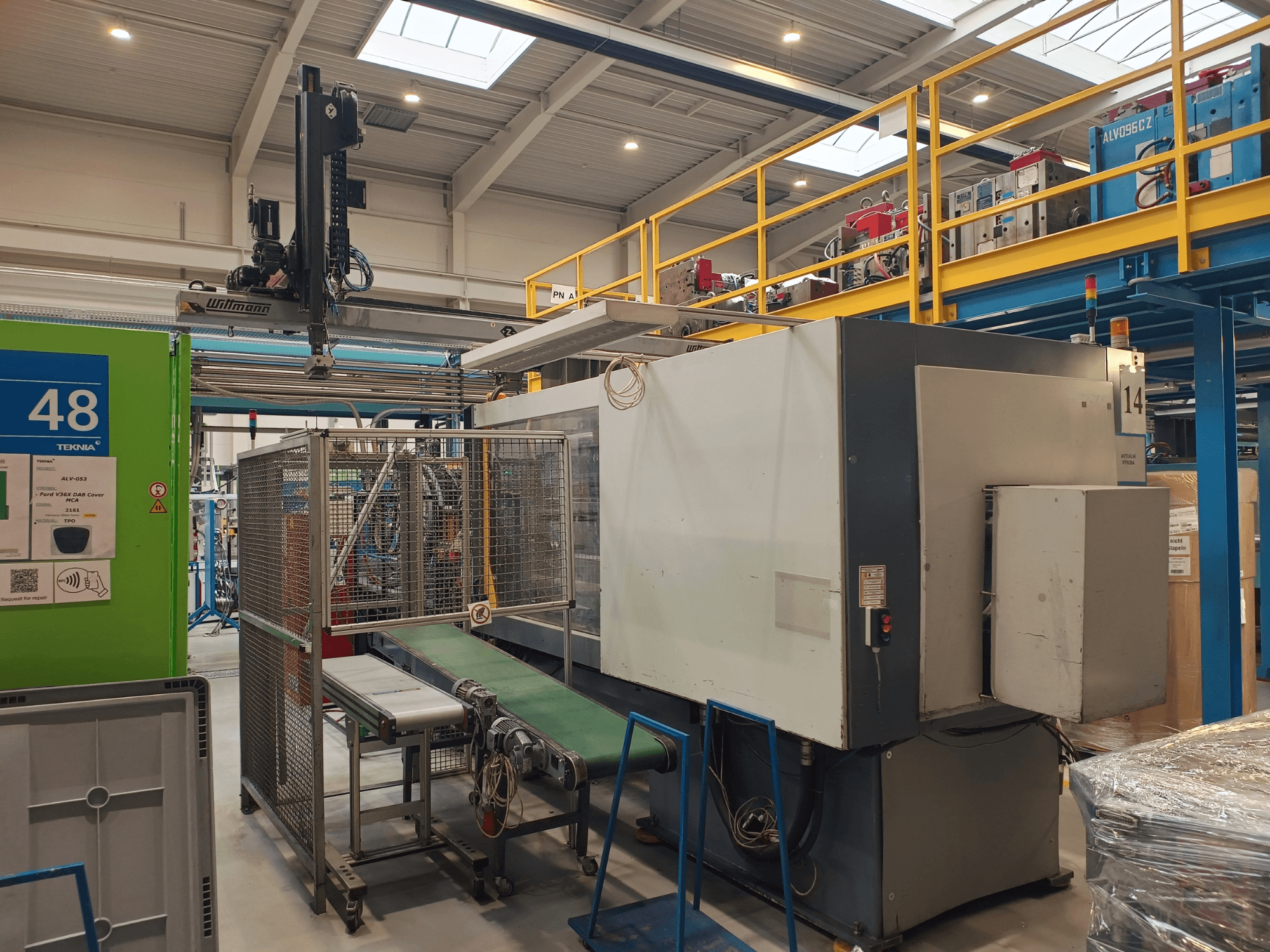 Industrial automation machine by Winmon, side view showing conveyor belt, control panel, and safety cage in a factory setting.