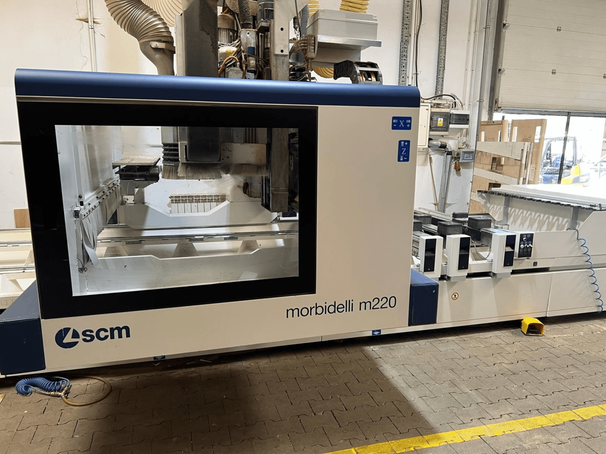 Front view of SCM Morbidelli M220 CNC Processing Center, showcasing a large window, control panel, and work area.
