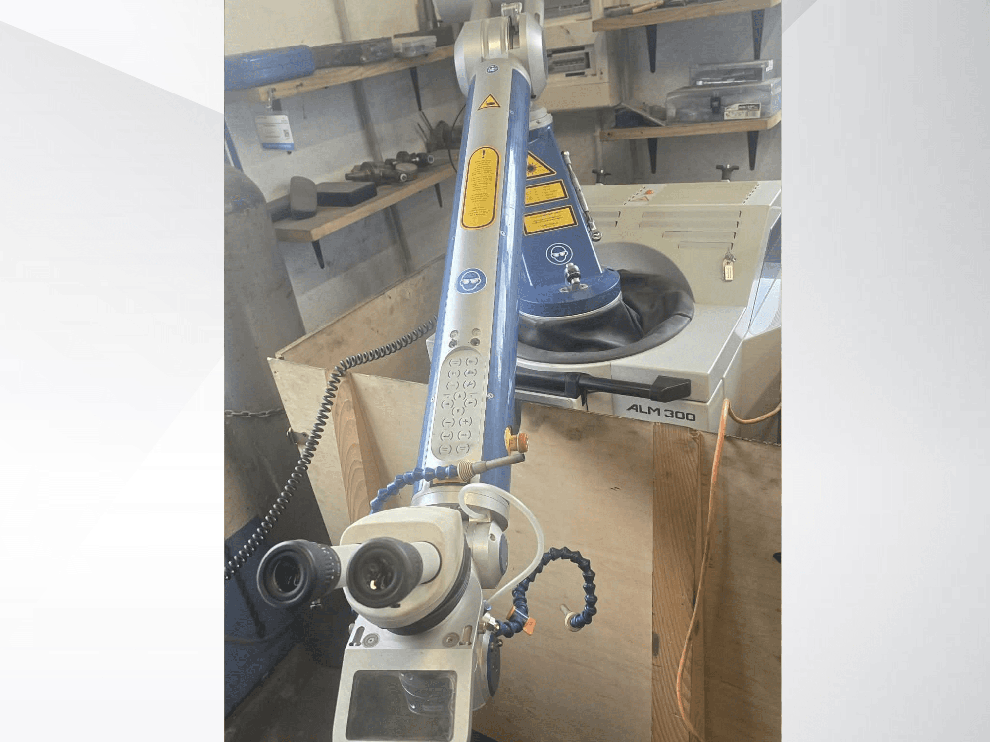 Front view of ALPHA LASER ALM 300 laser welding machine, featuring a robotic arm, optical lenses, and control panel.