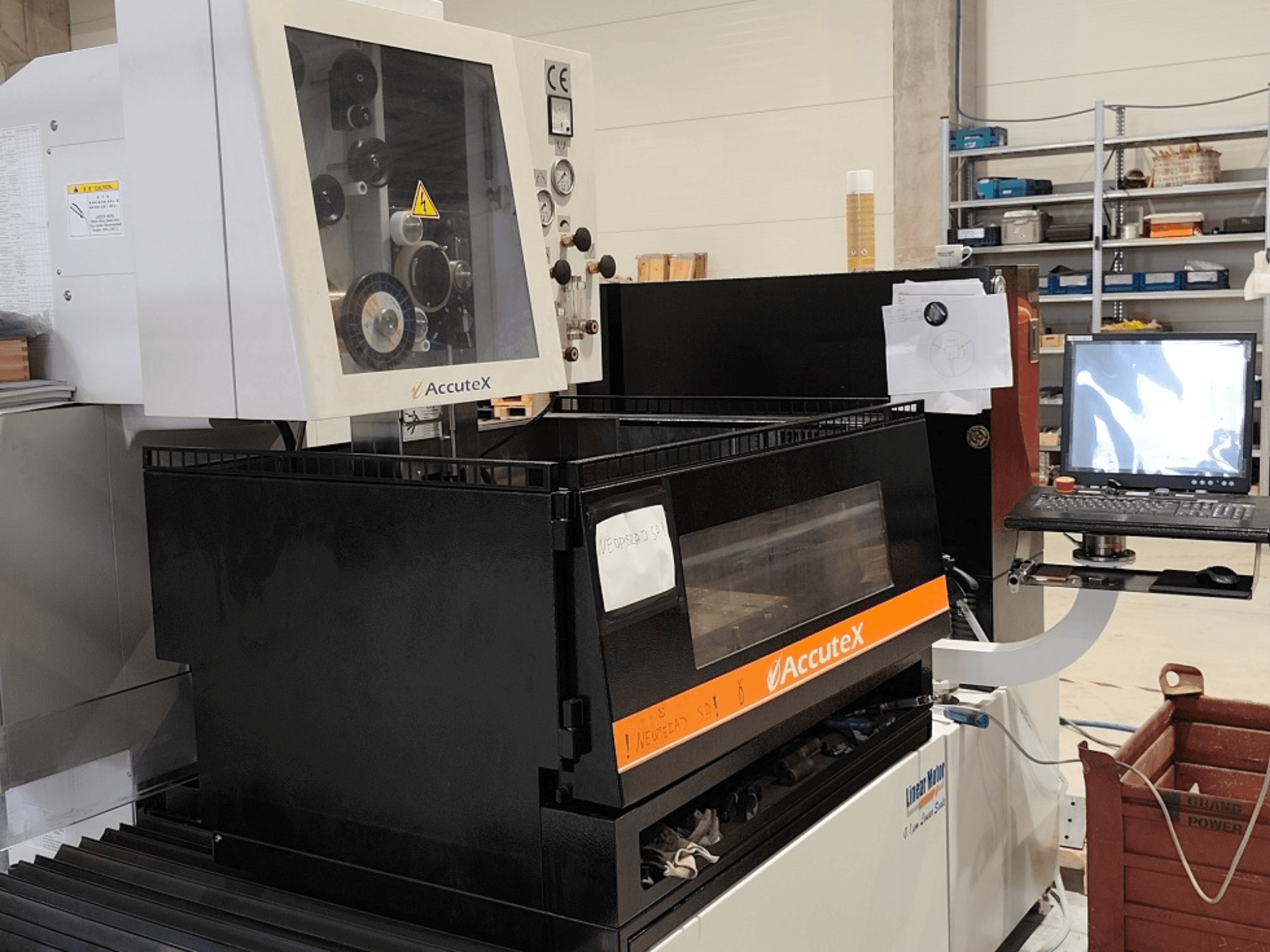 AccuteX AL-500SA Wire EDM machine in front view, featuring a control panel, specs label, and connected PC monitor.