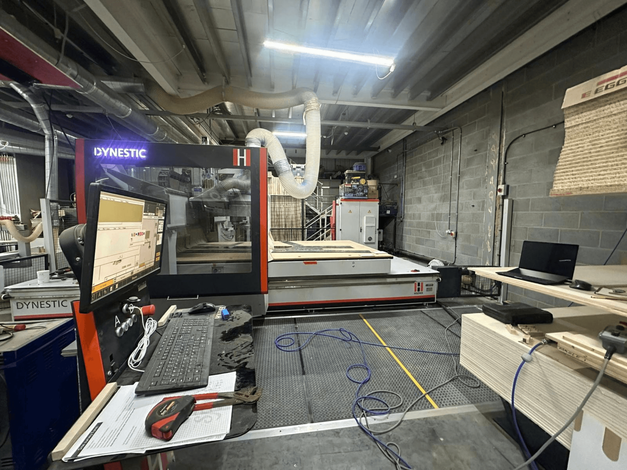 HOLZHER Dynestic 7535 wood mill in workshop, showcasing control panel, monitor, and materials on worktable, front view.