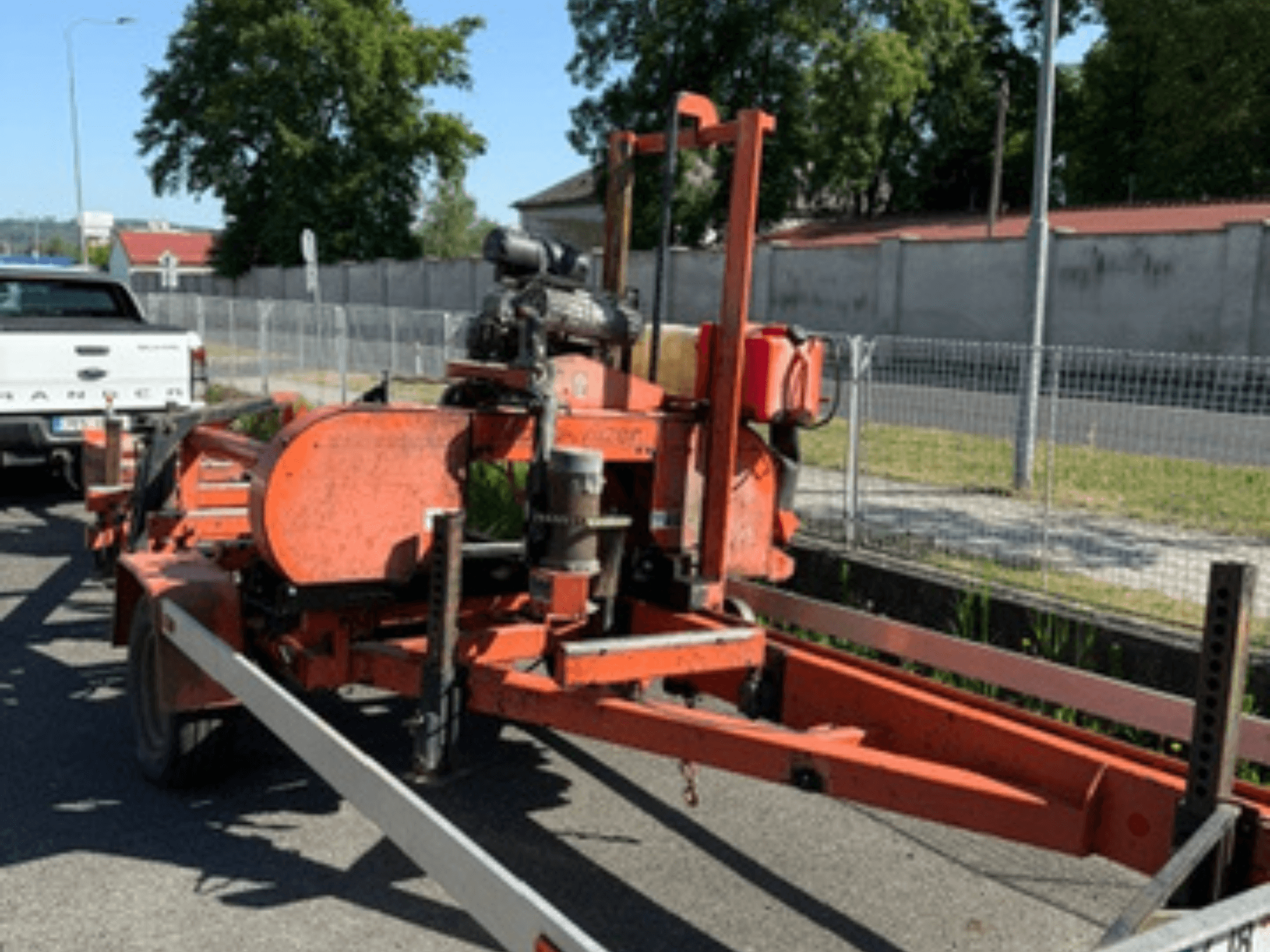 WOOD-MIZER LT40 wood band saw in orange, side view on a trailer with visible wheels and engine components.