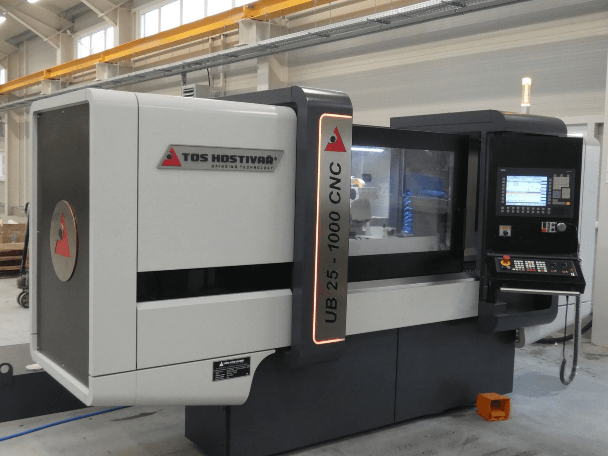 Cylindrical grinding machine TOS HOSTIVAR UB 25-1000/C shown in front view, featuring a control panel and grinding wheel.