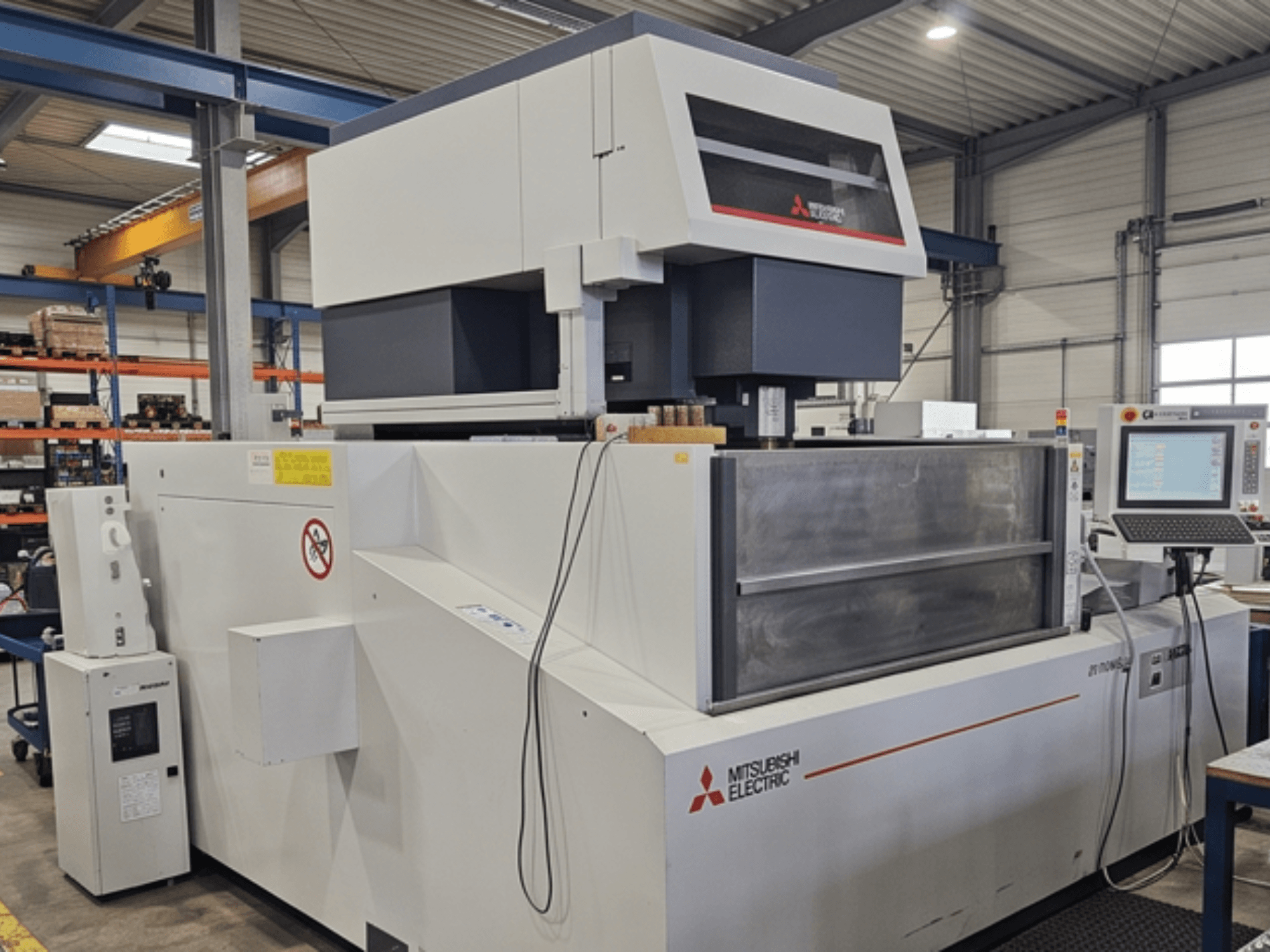 Mitsubishi MV-4800 Wire EDM machine, front view, showcasing control panel and work area in a factory setting.