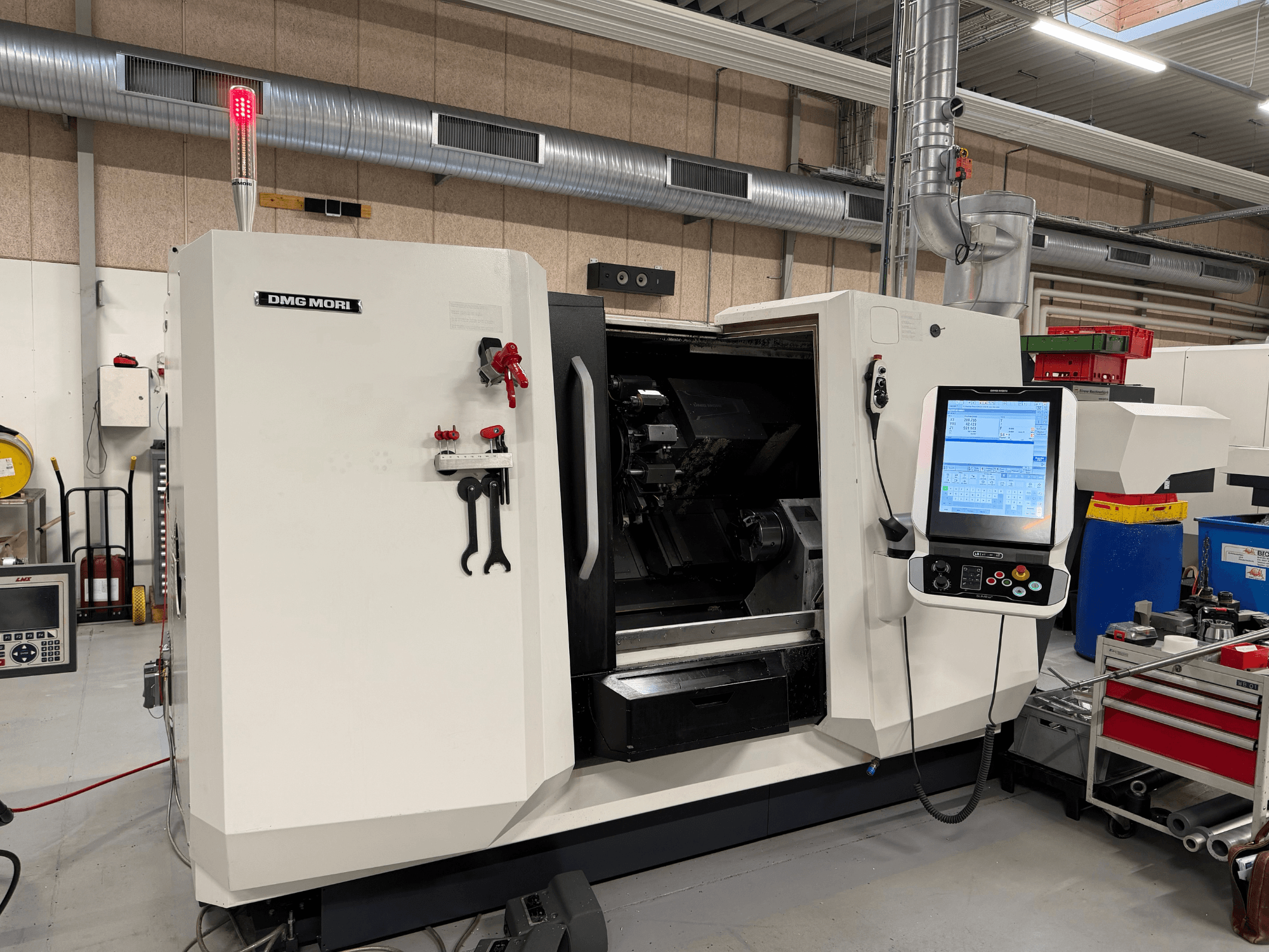 DMG MORI CLX 450 V6 horizontal turning machine, front view with control panel, emergency stop, and safety light visible.