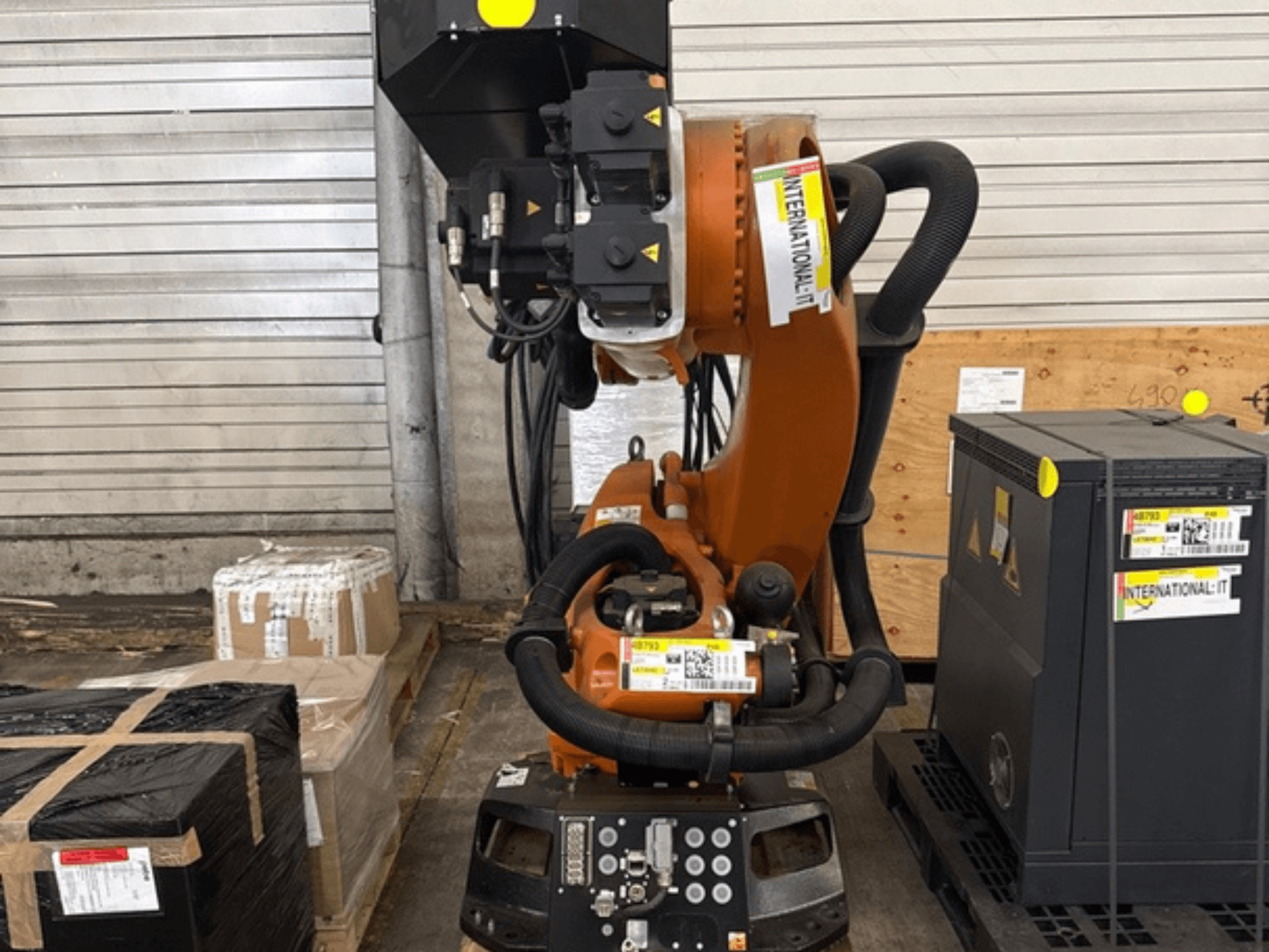 KUKA KR 210 R2700 extra robot arm in front view, displayed on a pallet beside packages and equipment.