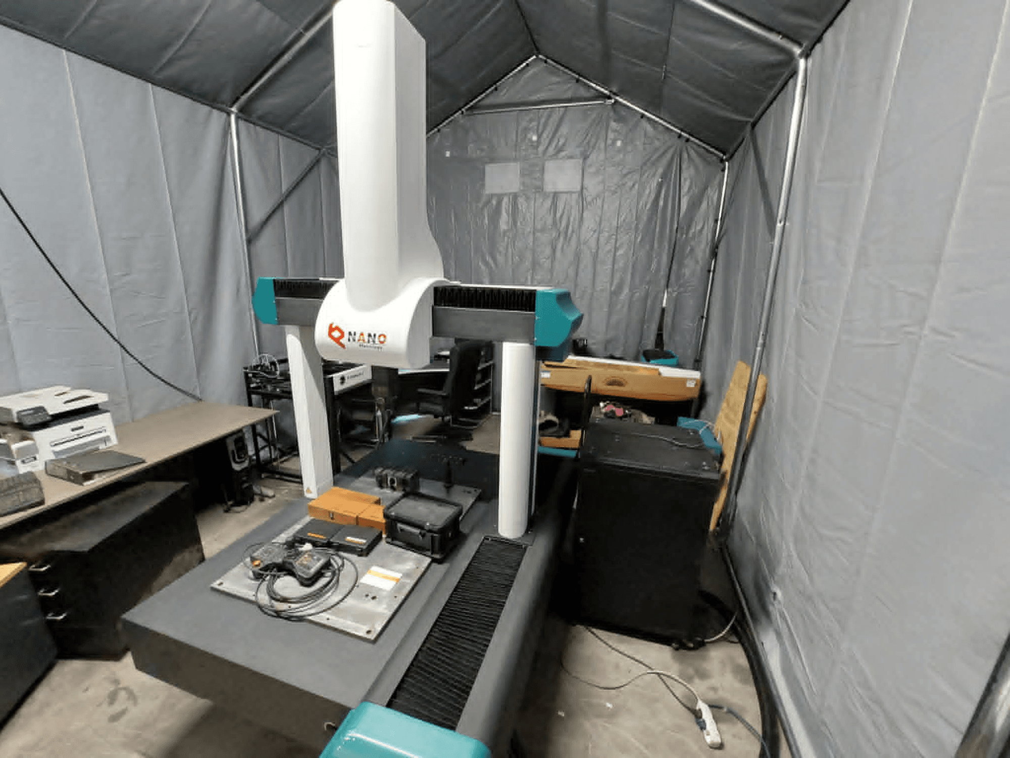 NANO METROLOGY Micr 7106 CMM in a tent; front view showing the machine's arm and measurement platform with accessories.