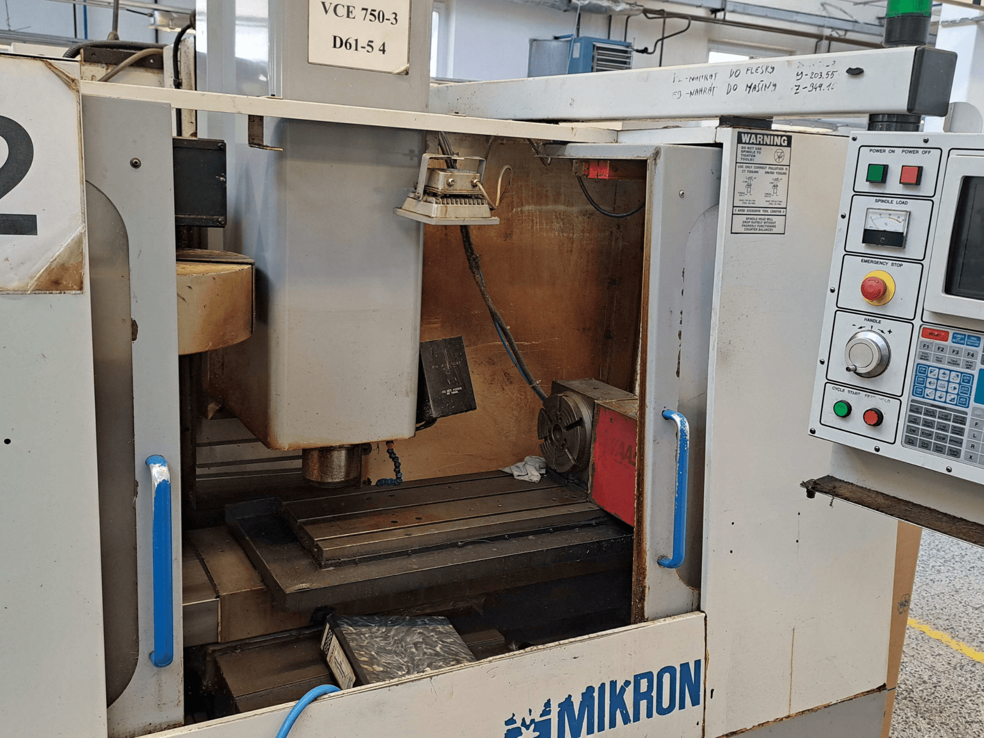 Front view of a Mikron VCE 750-3 milling machine, showing the spindle, control panel, and worktable with technical details.