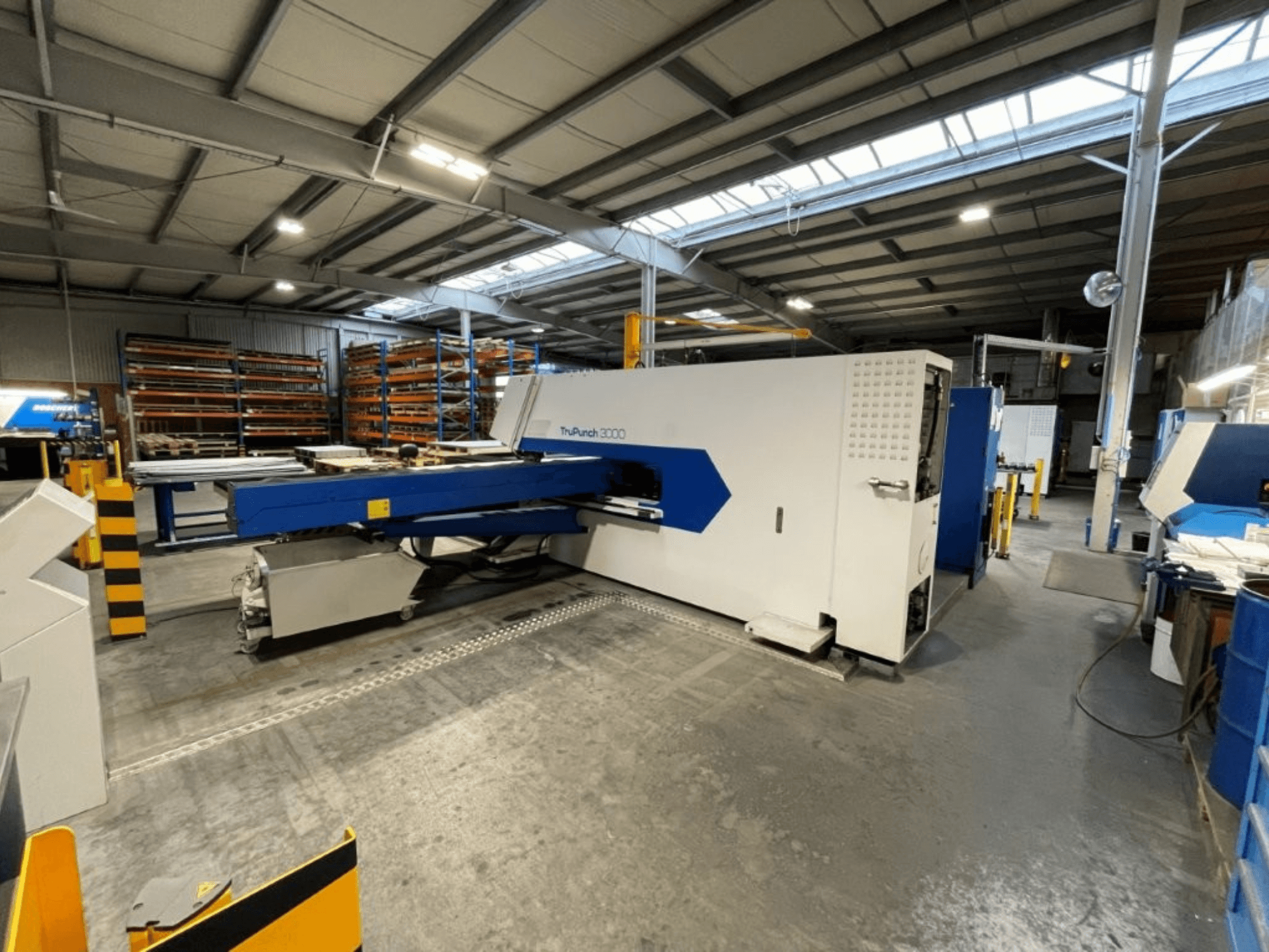 CNC Punch Press TRUMPF TruPunch 3000 in a factory setting, front view showcases its blue and white design and operational components.