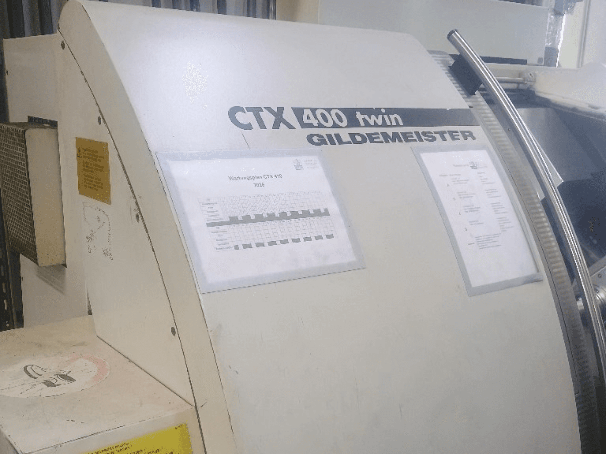 Gildemeister CTX 400 twin horizontal turning machine, front view, showing operational panels and technical documentation.