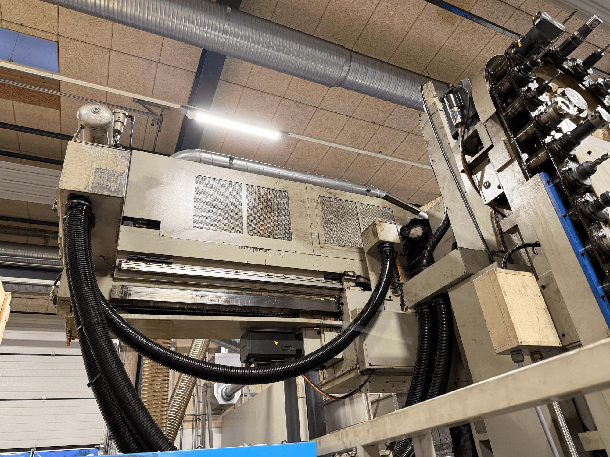 Alt text: KIHEUNG KNC-U1000 Universal Machining Centre in a side view, showcasing machinery components and tubing.