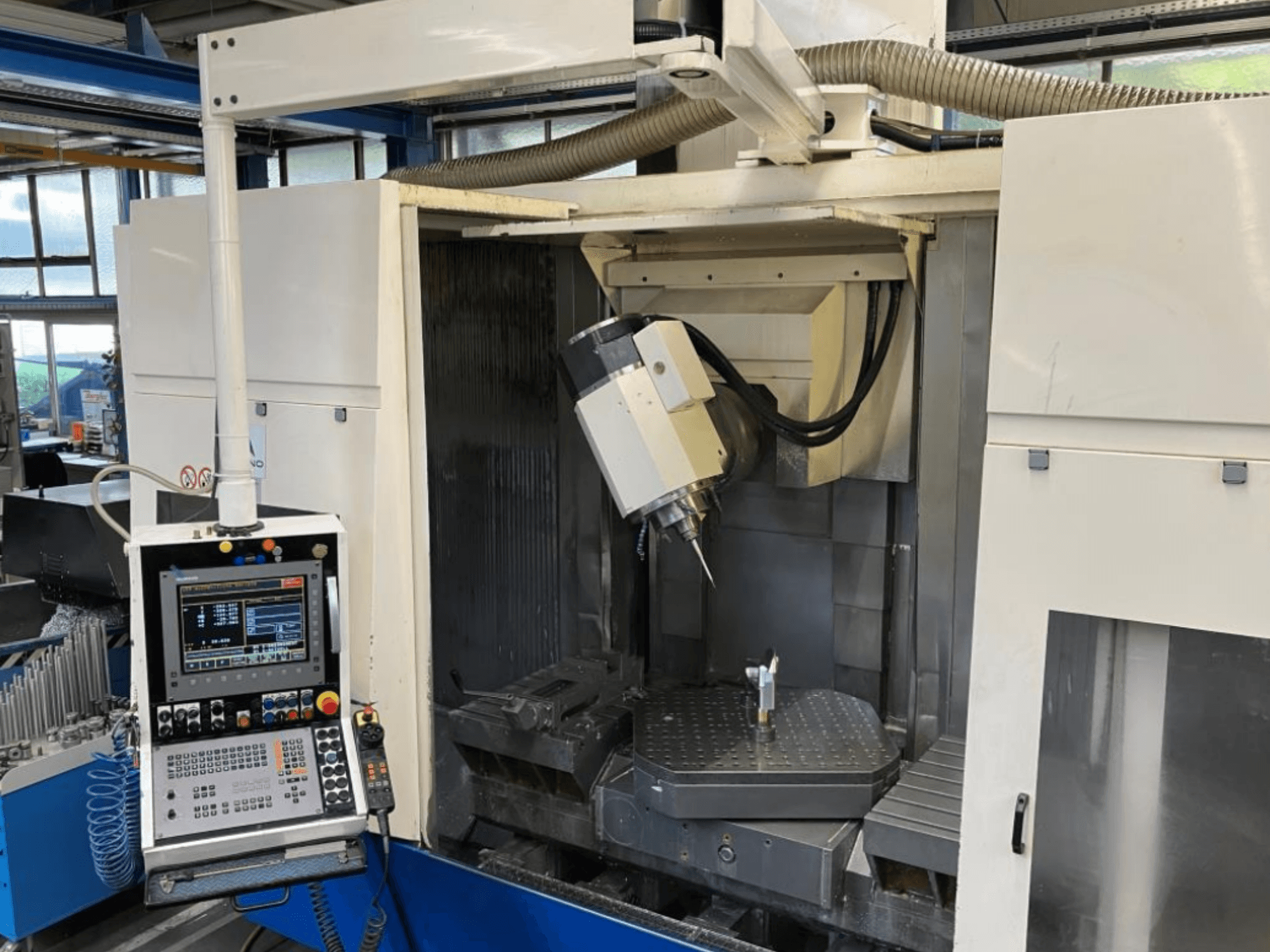 Huron EX-C universal machining center, front view, displaying control panel, spindle head, and workpiece setup on the table.
